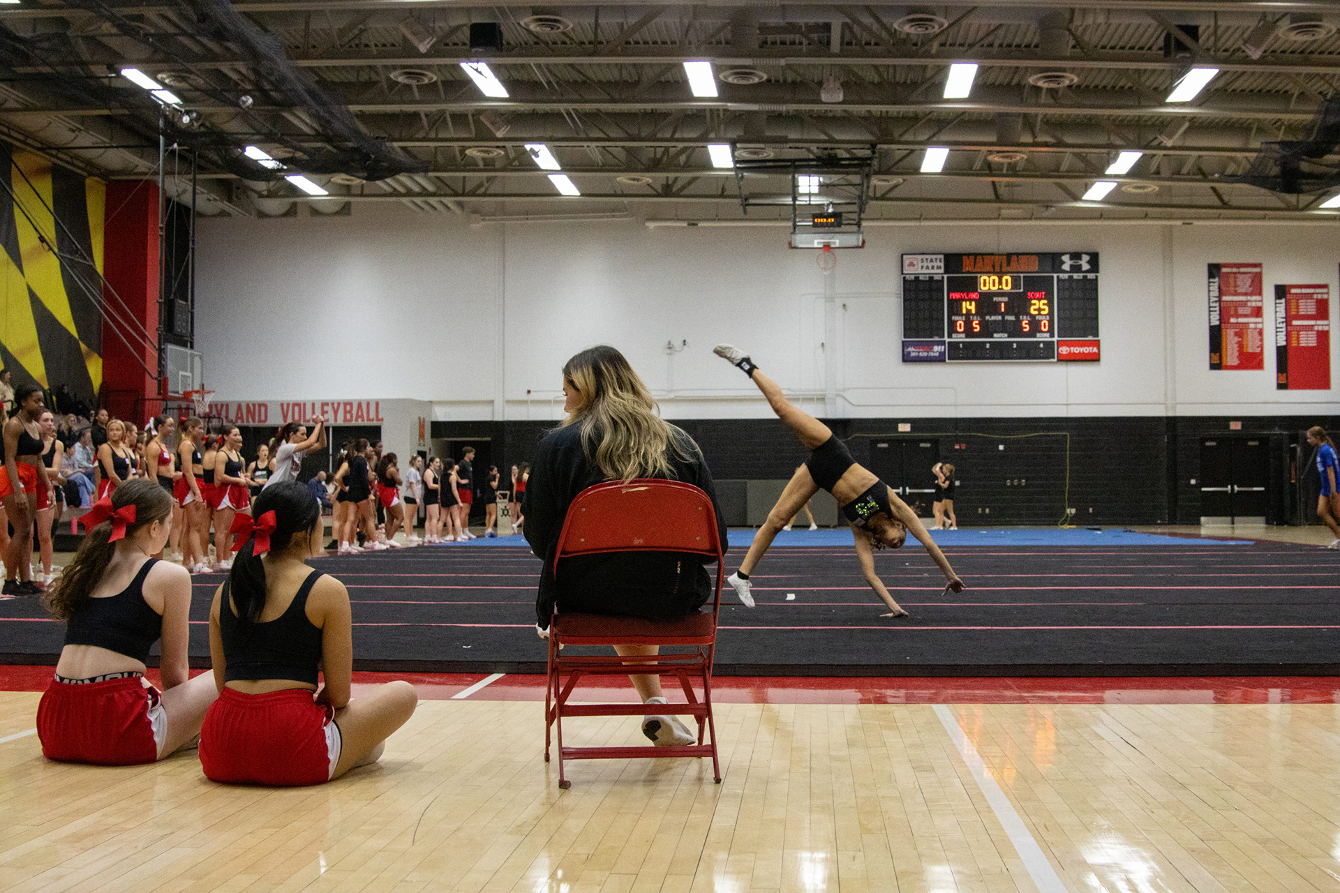 Assistant cheer coach Katie Hill and two Maryland cheerleaders watch high school cheerleaders practice their tumbling passes on March 7, 2025.