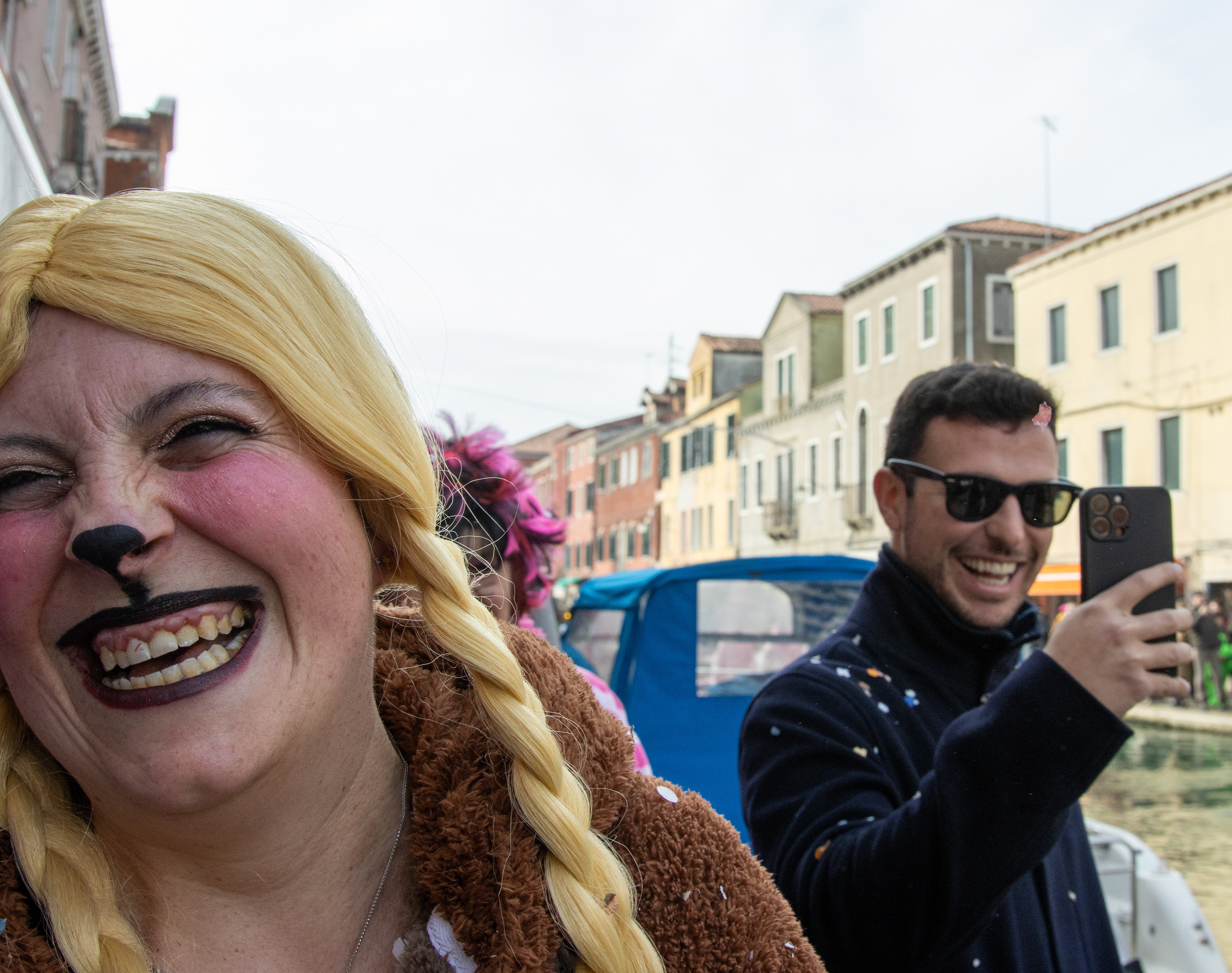 A woman laughs after throwing confetti at an unsuspecting passerby at Carnevale in Venice, Italy on Feb. 8, 2026.