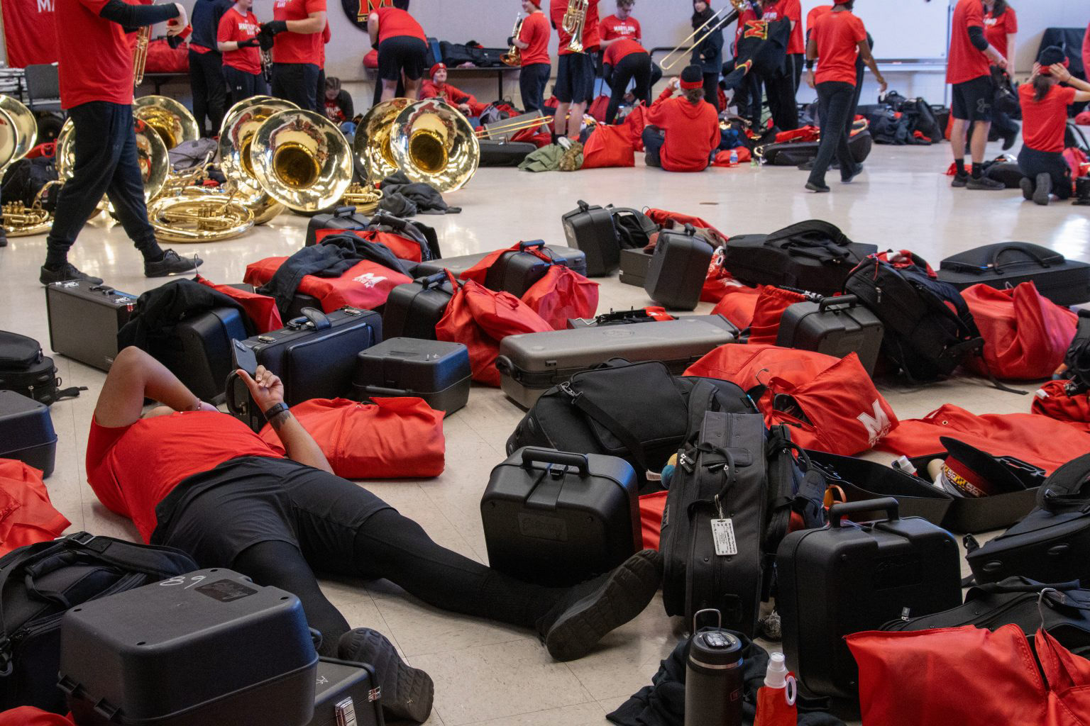 A member of the Mighty Sound of Maryland takes a break to scroll on their phone between afternoon rehearsal and pre-game festivities inside The Clarice Smith Performing Arts Center on Nov. 16, 2024. Football game day preparations for the University of Maryland’s marching band begin several hours prior to the kickoff time and are packed with rehearsals and fan performances to inspire Maryland pride. 