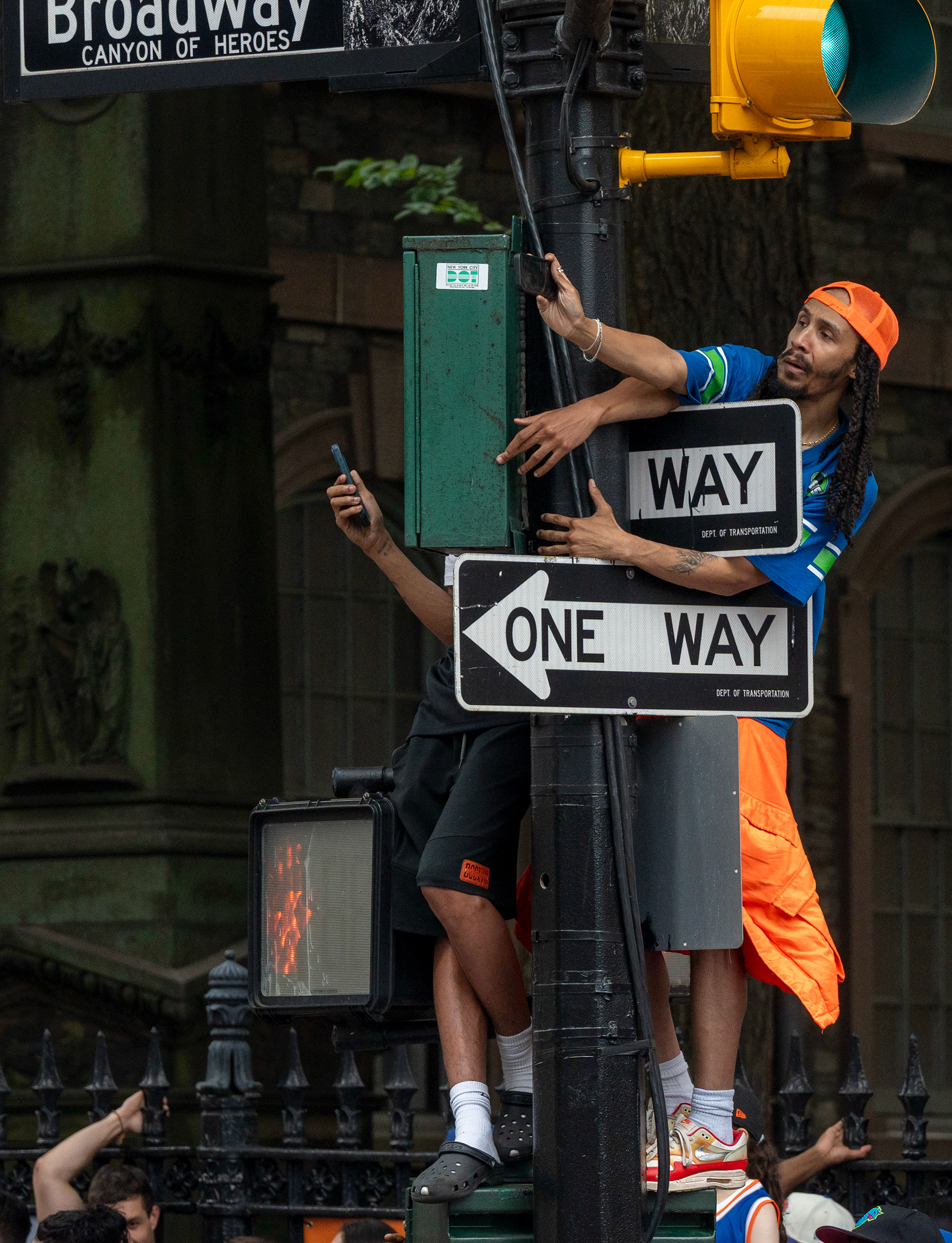 Spectators climb street poles for a better view at the New York Knicks championship parade in New York City, NY, USA on Jun 18, 2026.