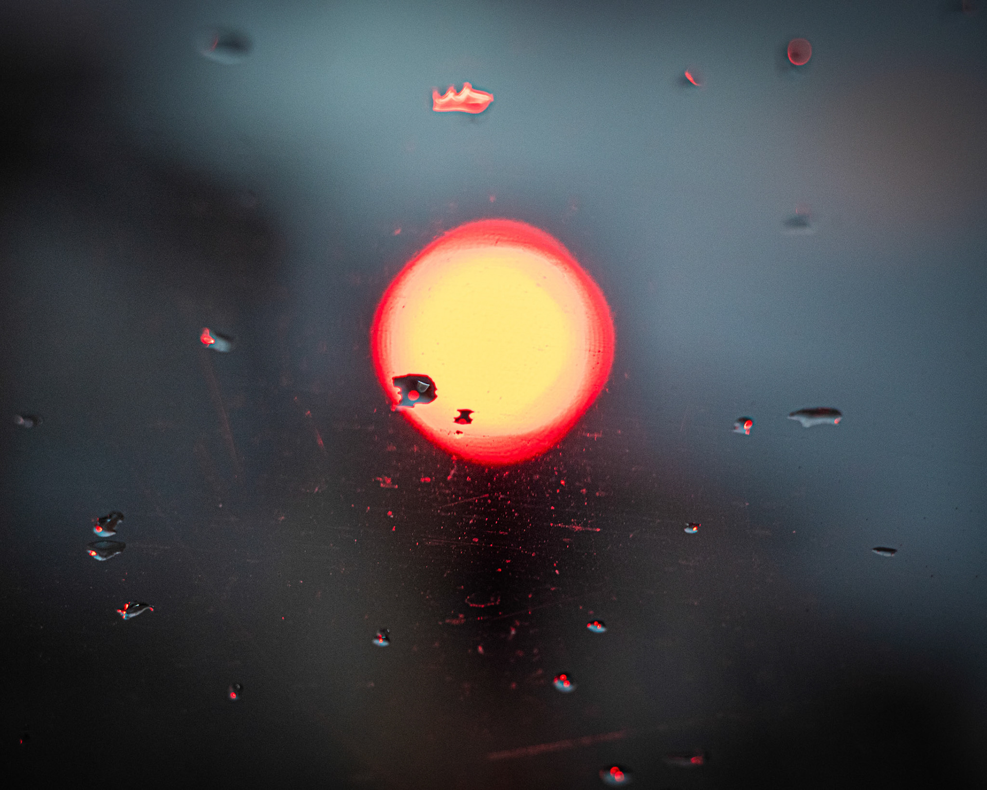 Yağmurlu bir akşam, trafikte kırmızı ışıkta beklerken camdaki yağmur damlalarına ve kırmızı ışığın yarattığı bokeh etkisine kapıldım. Bu soyut görüntü, adeta bir ressamın fırçasından fırlamış gibiydi. Kırmızı ışık, yağmur damlaları ve camın dokusu bir araya gelerek, gerçeküstü bir atmosfer yaratmıştı.