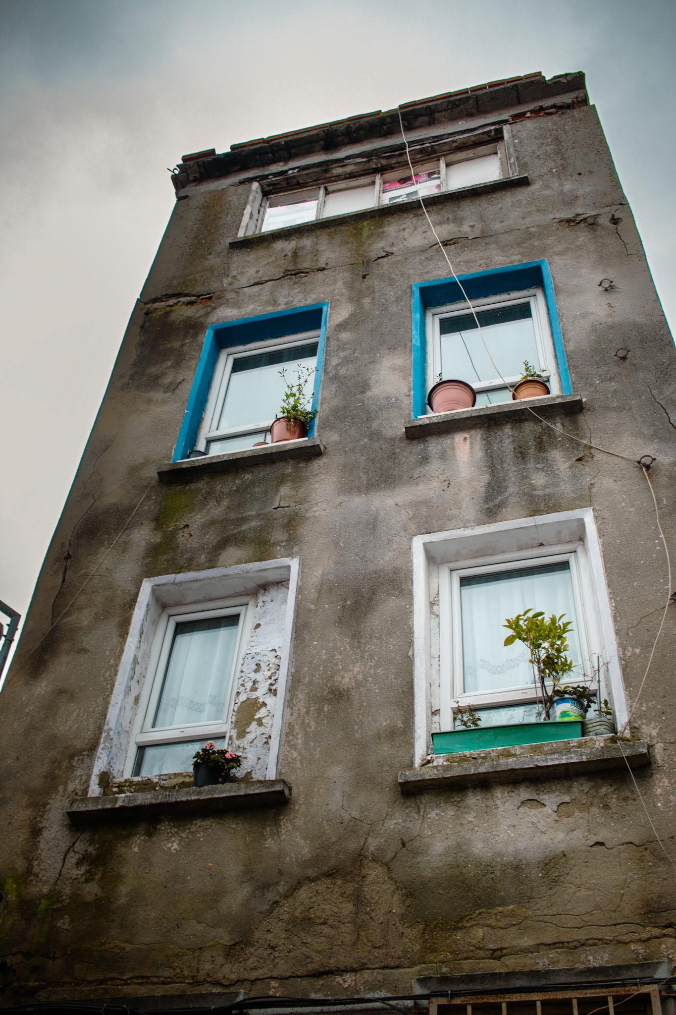 Balat'ın tarihi sokaklarında, zamanın izlerini taşıyan eski bir ev dikkat çekiyor. Evin her camı farklı renklere boyanmış, saksılarla bezenmiş pencerelerinde hala yaşamın izleri var. Bu harabe ev, şehrin geçmişine ve yaşanmışlıklara dair bir pencere açıyor. Renkli camlar ve saksılar, bu tarihi yapının hüzünlü atmosferine umut ve neşe katıyor.