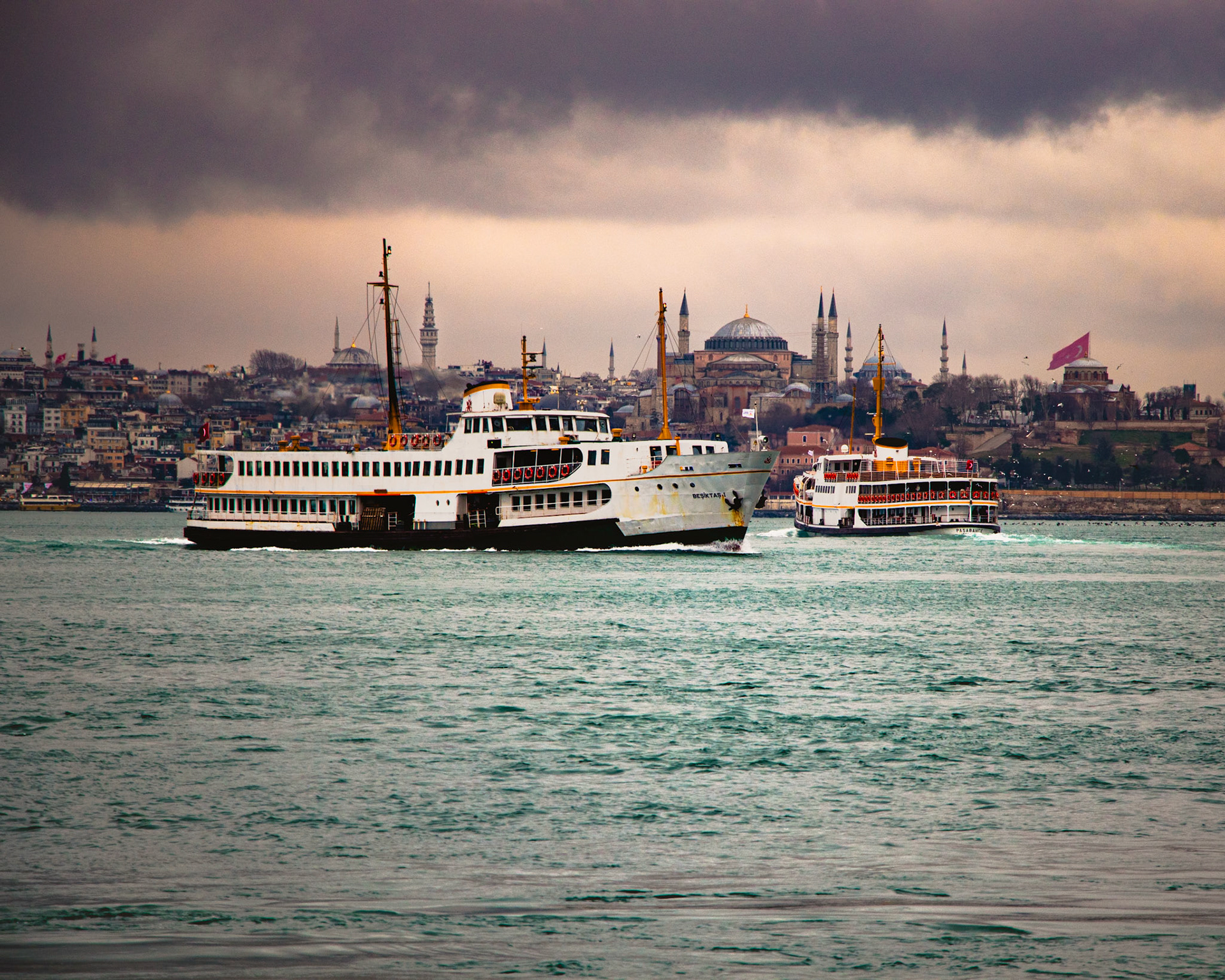 Tarihin ve ihtişamın sembolü Ayasofya'nın gölgesinde, iki vapur karşı istikamette yan yana geçiyor. Bu kare adeta bir tabloyu andırıyor. Bir yanda tarihi caminin ışıl ışıl silueti, diğer yanda iki vapurun heybetli duruşu, şehrin tarihi ve modern yanlarını bir araya getiriyor. Vapurun yorulmuş paslı görüntüsü ve denizin dalgaları ise bu manzaraya ayrı bir güzellik katıyor.