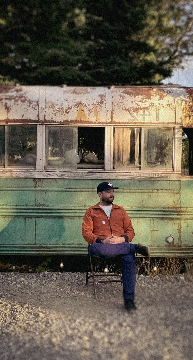 Cody Moiseve sitting in front of a bus in Alaska