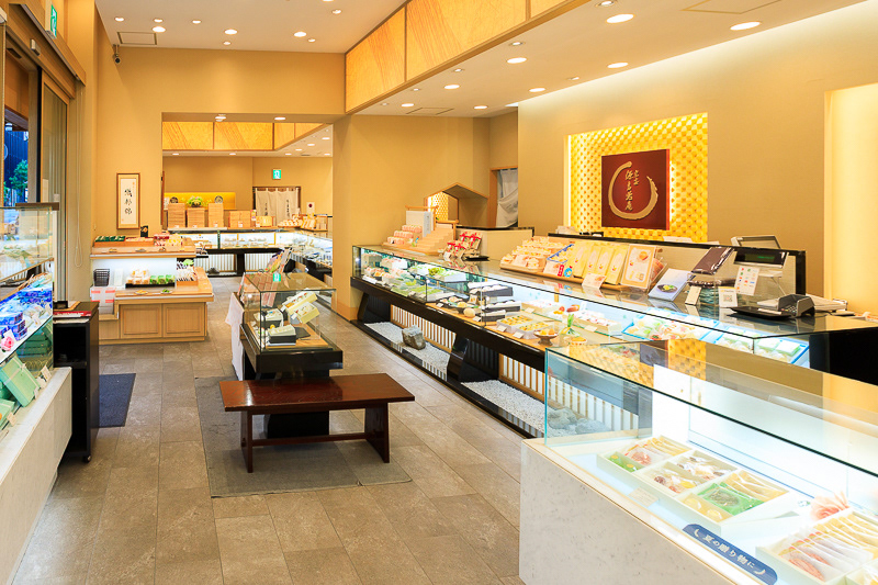 ショーケースに商品が並ぶ菓子店の店内写真。温かみのある照明と店舗空間の雰囲気を表現。