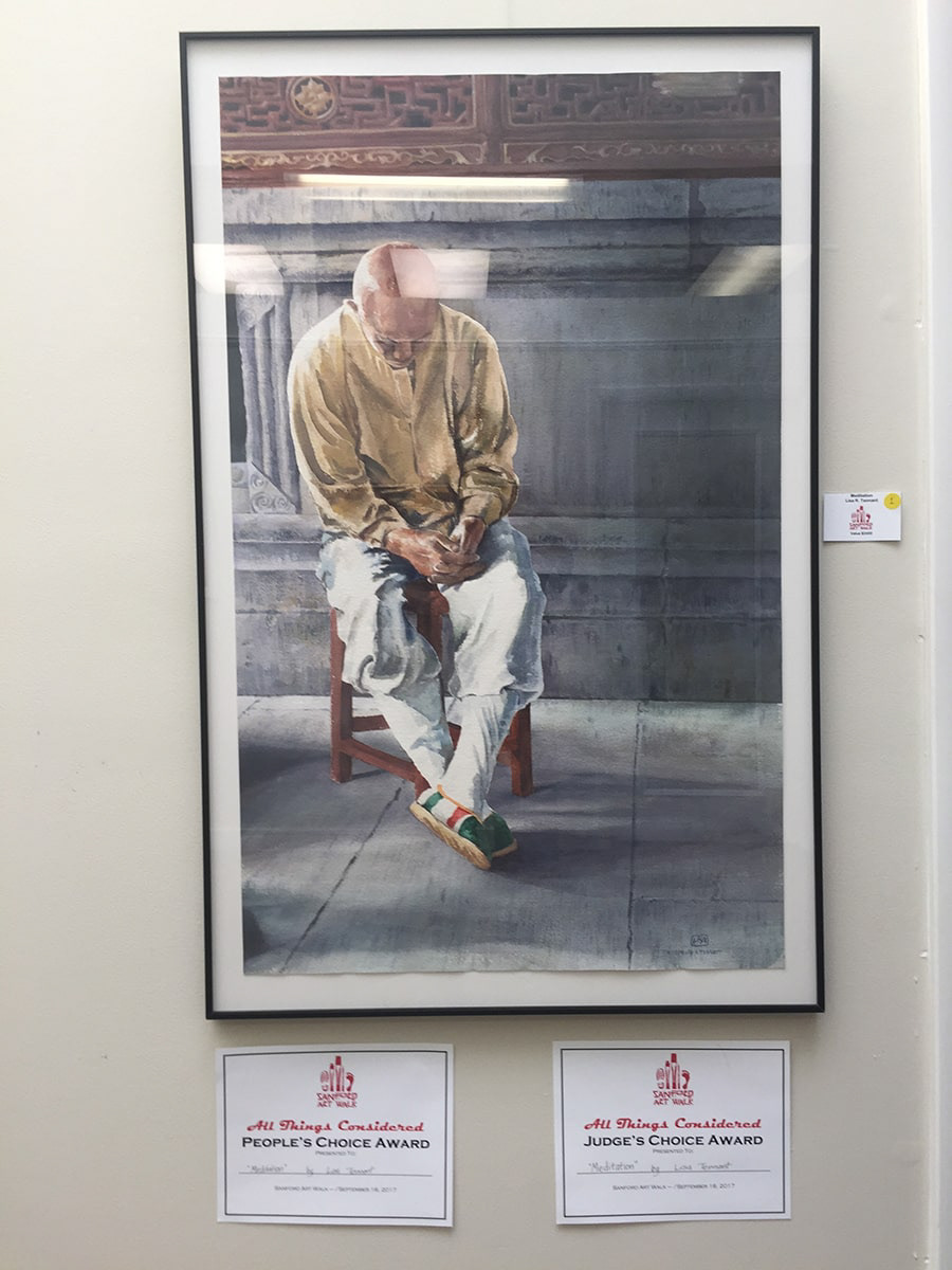 image of the painting shown hung on a wall of the gallery with award certificates