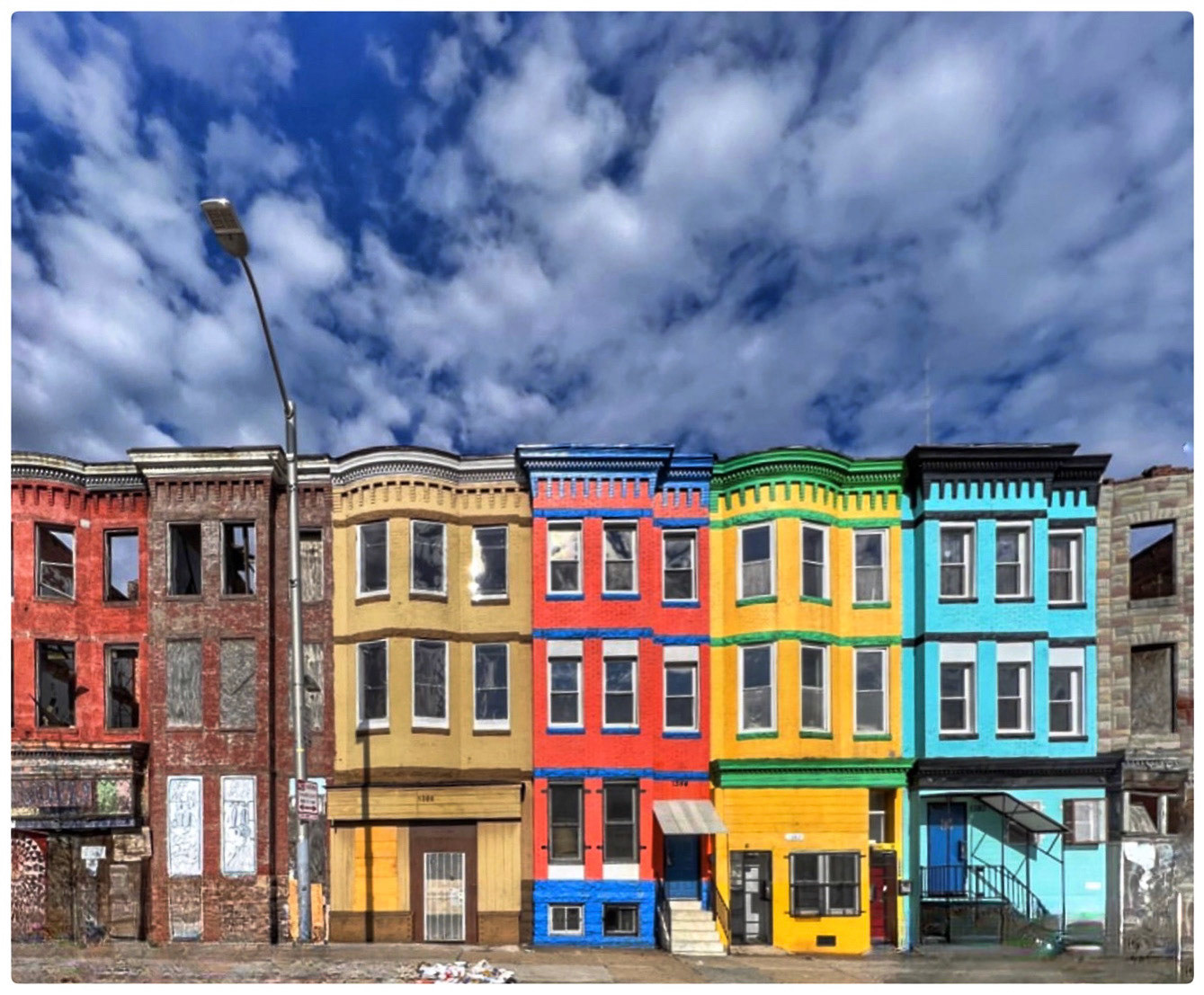 West Baltimore - Bright properties next to abandoned dwellings under busy skies.