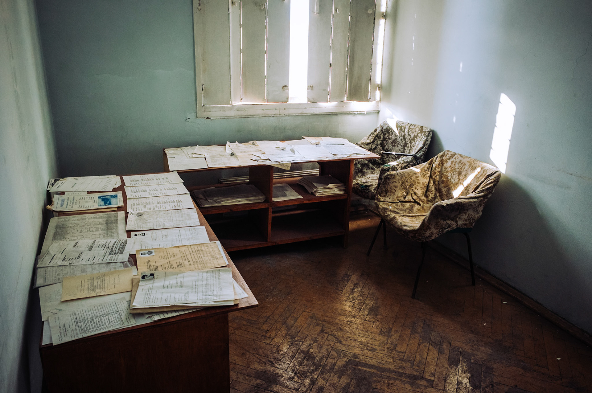 Ein Stapel alter Akten und Papiere liegt auf einem Schreibtisch in einem verlassenen Büro in Pyramiden, Spitzbergen. Die vergilbten Dokumente sind Überreste der sowjetischen Verwaltungszeit in der Arktis.