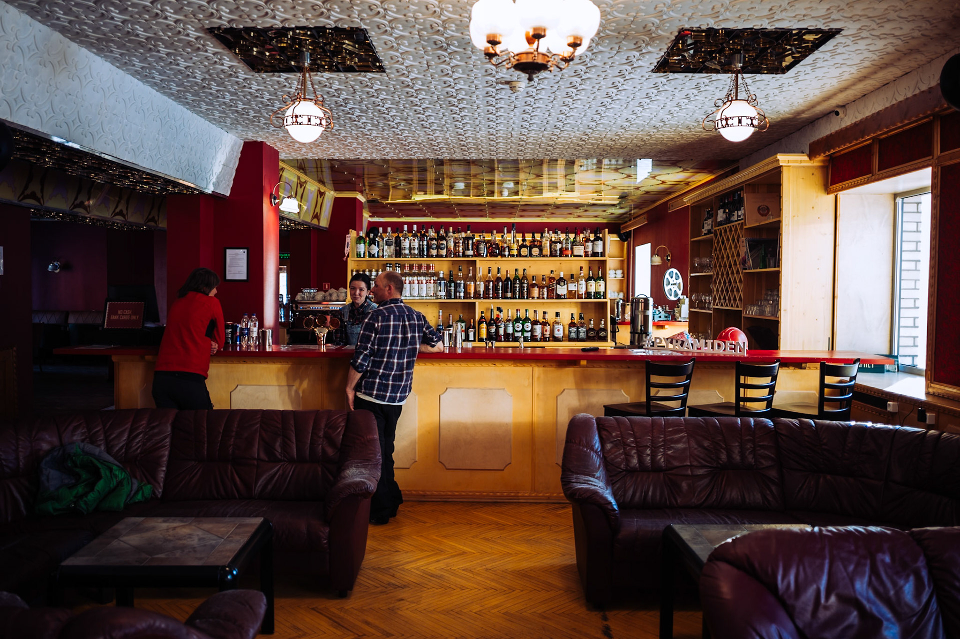 Eine Bar in einem Hotel in Pyramiden mit einer Auswahl an Spirituosen und Getränken. Das Interieur kombiniert rustikale und moderne Elemente.