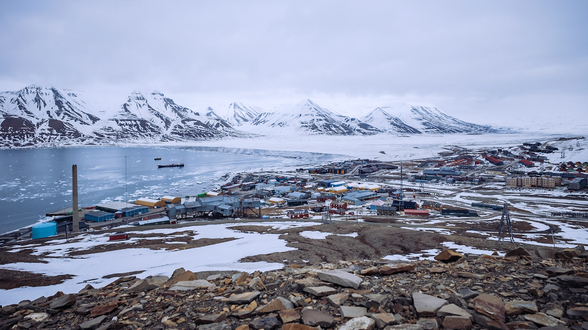 Ein Blick auf Longyearbyen von oben, mit einer Mischung aus bunten Häusern, verschneiten Straßen und dem Meer im Hintergrund.