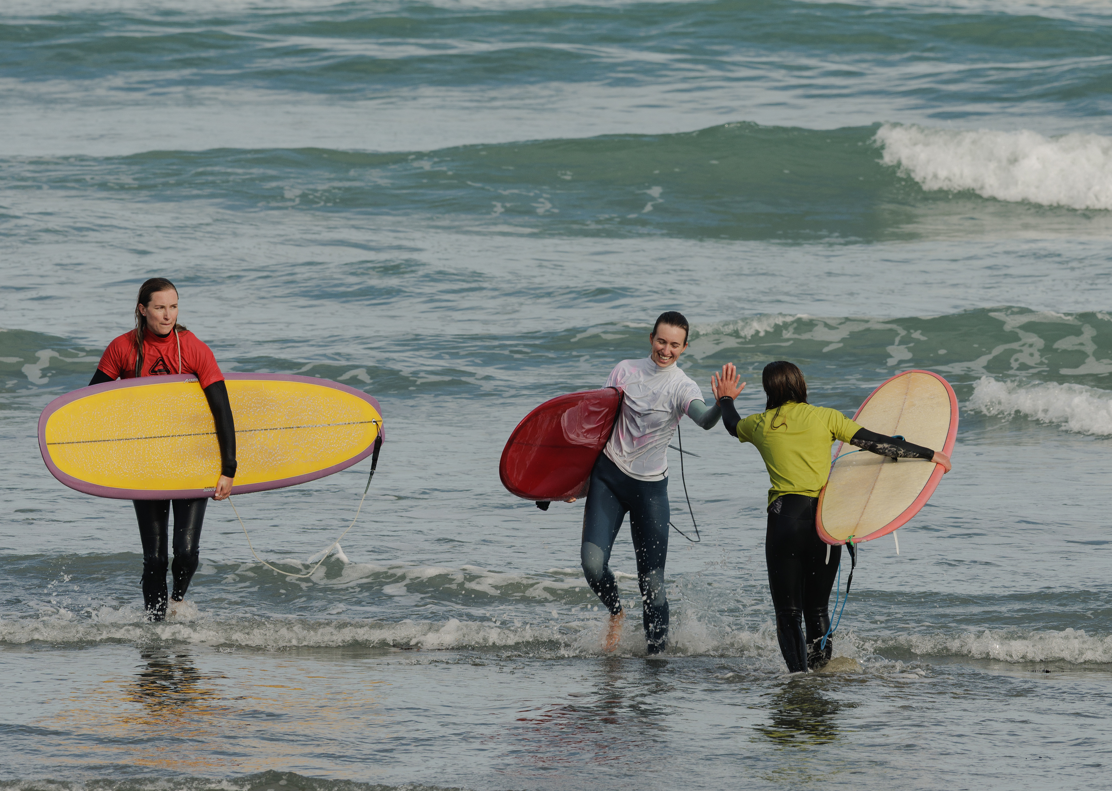 Surfers meet in the shallows to high-five after their competition heat.
