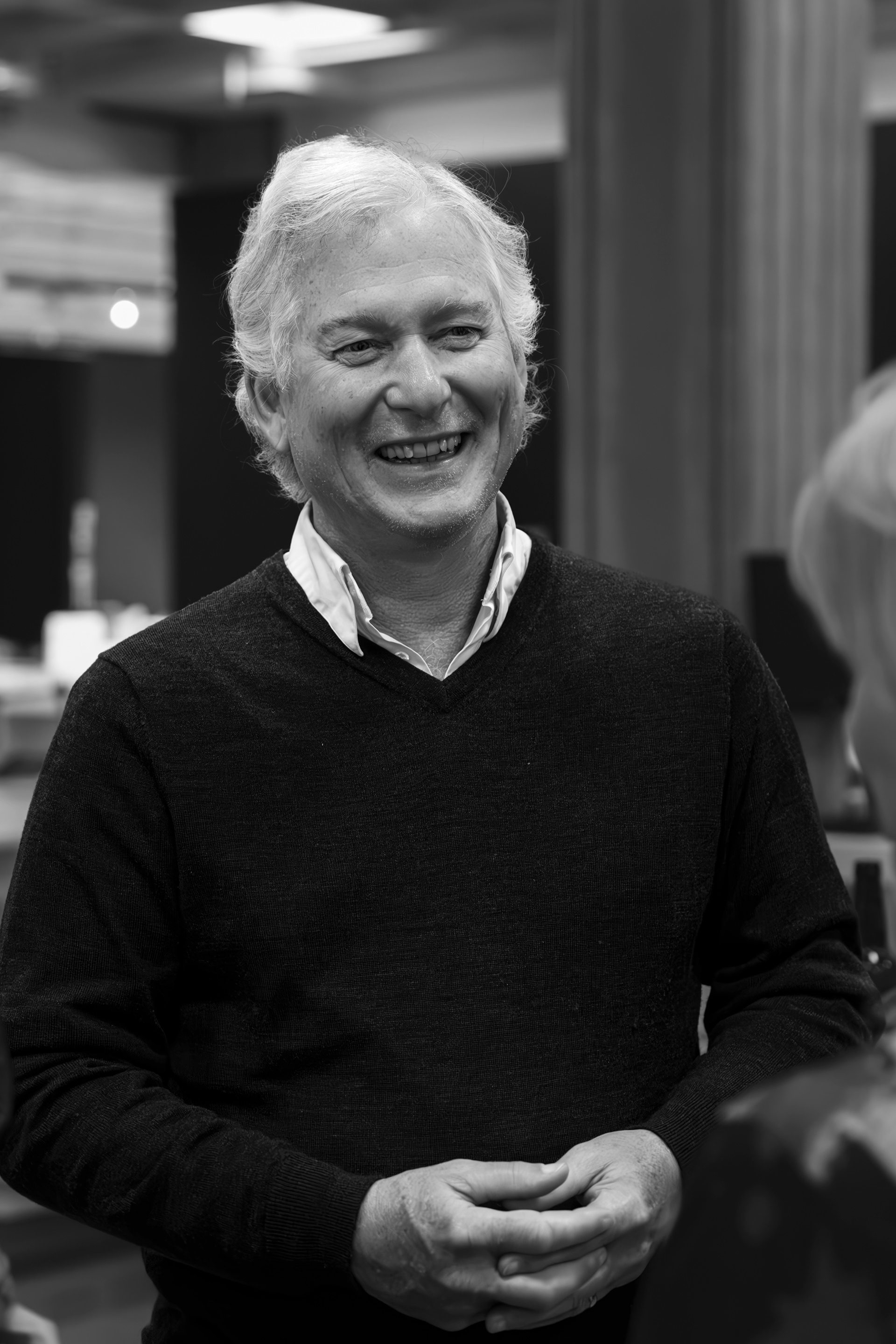 A man in a dark woollen top smiles as he chats to other attendees