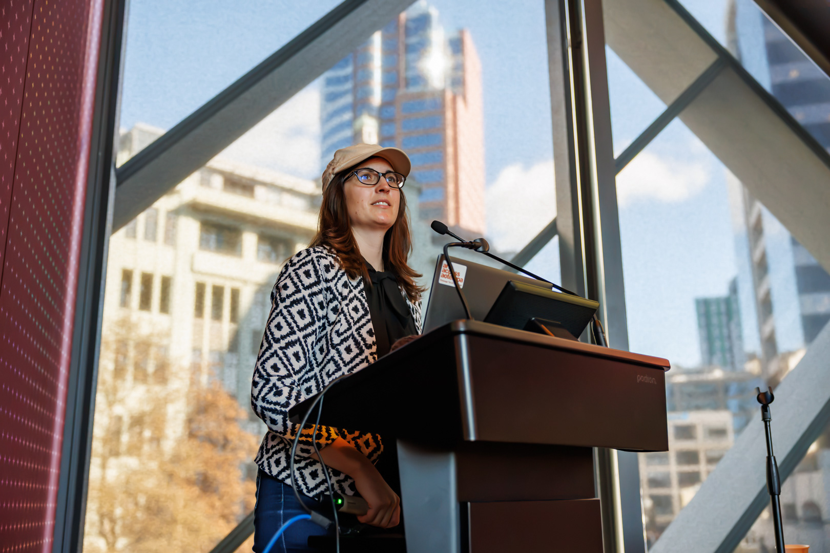 Arts For All Activator, Katie Querin, stands at a podium and addresses the crowd with Wellington in the background.