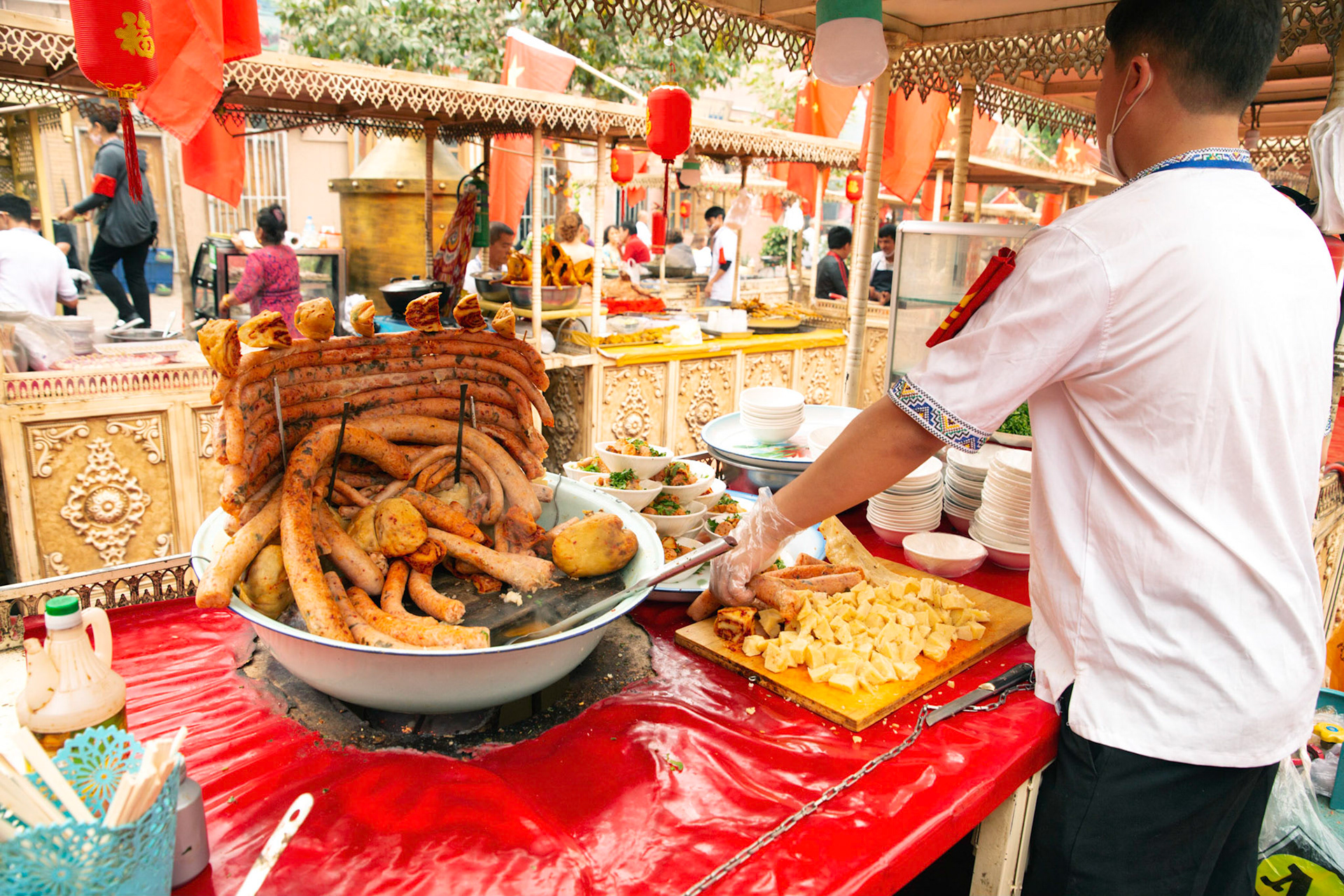 kashgar, Xinjiang, China - September 5, 2018: Food stall Kasghar food market, The dish is called opkehessip, stuffed lamb lungs served with sauce.. Man preparing food.