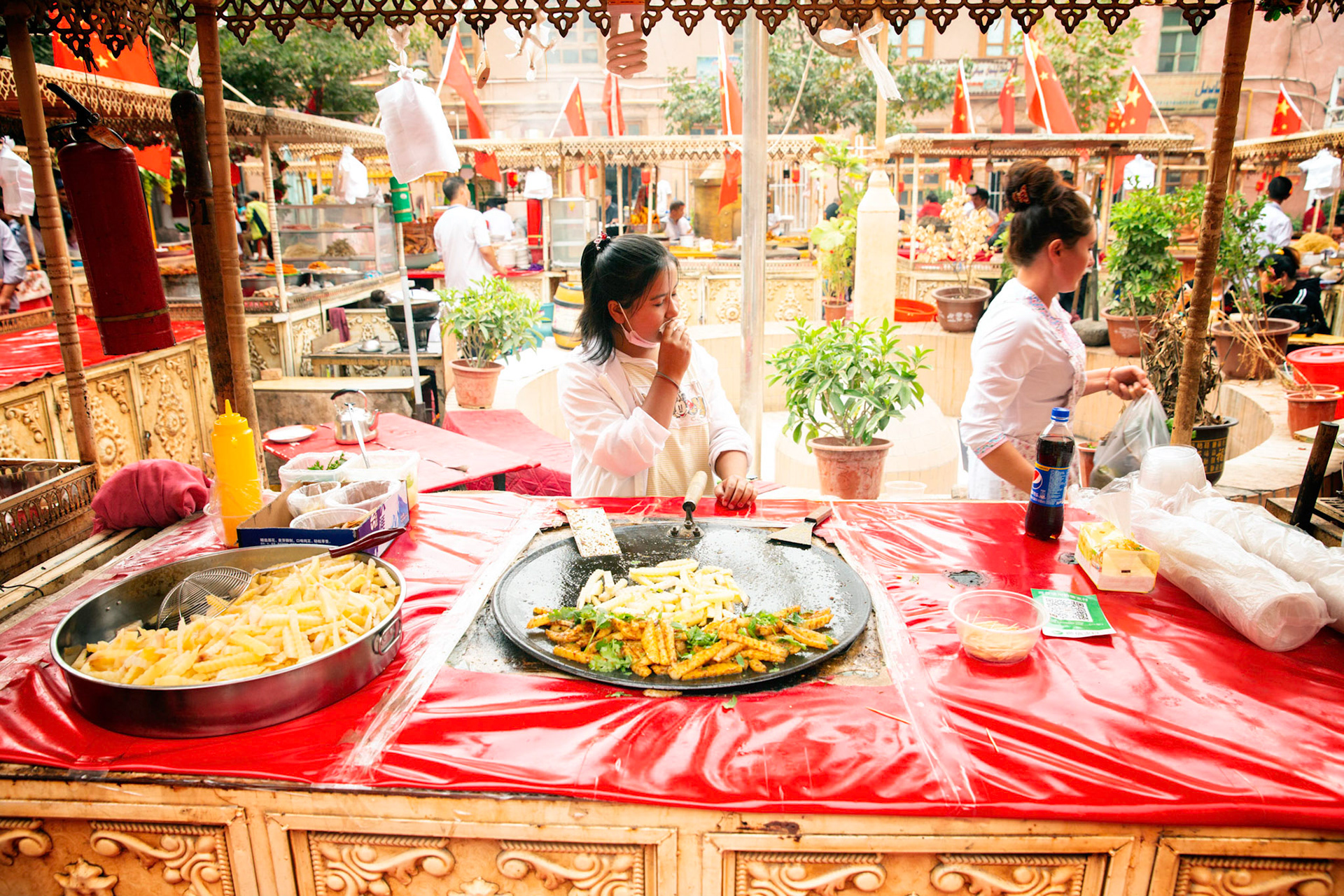 Kashgar, Xinjiang, China - September 5, 2018: Vegetable snacks at the Kasghar food market, not the abundance of chinese flags in the background