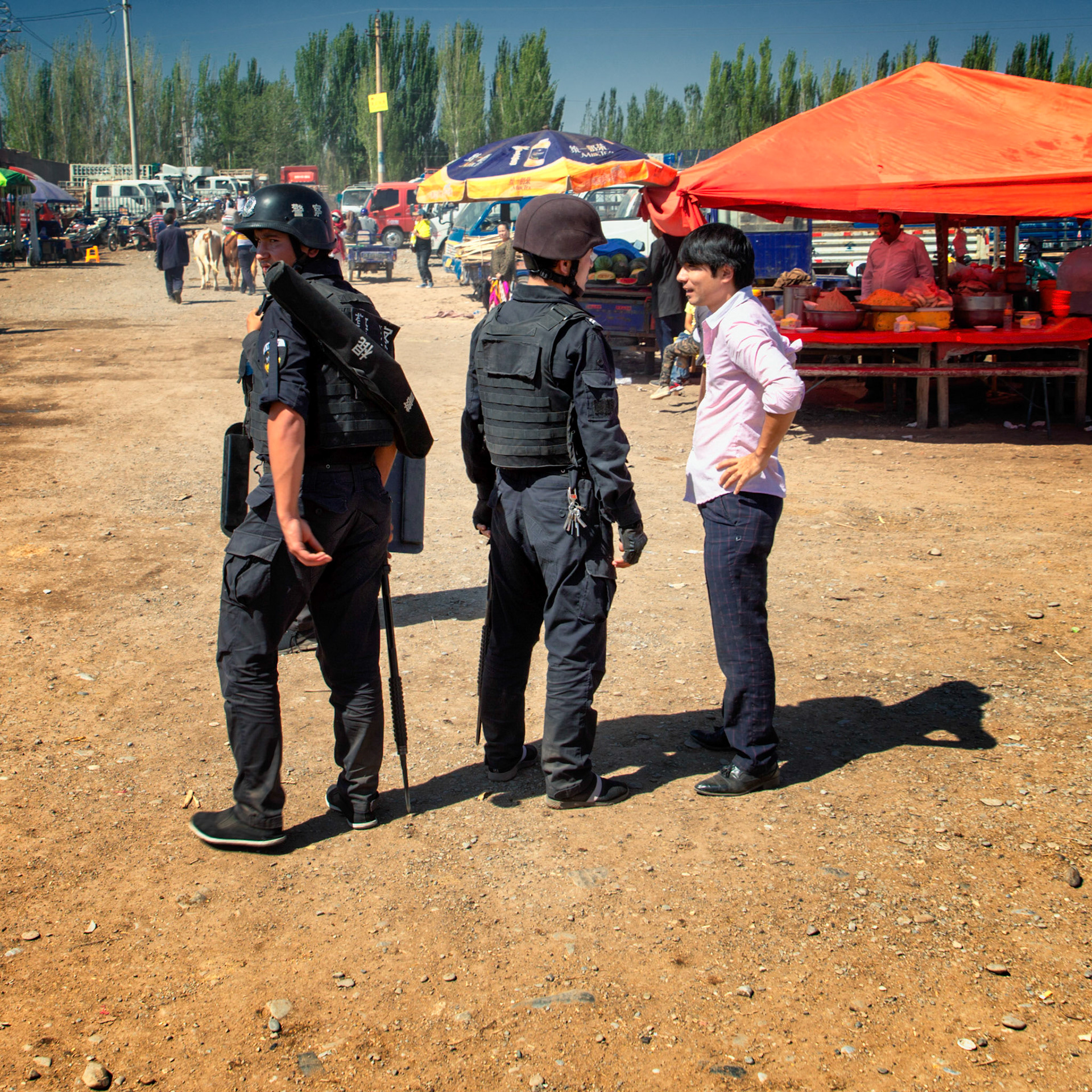 Kashgar,  China - September 9th, 2018 : Small group of security police patrolling the Kashgar sunday bazaar (sunday cattle market), carrying iron batons.