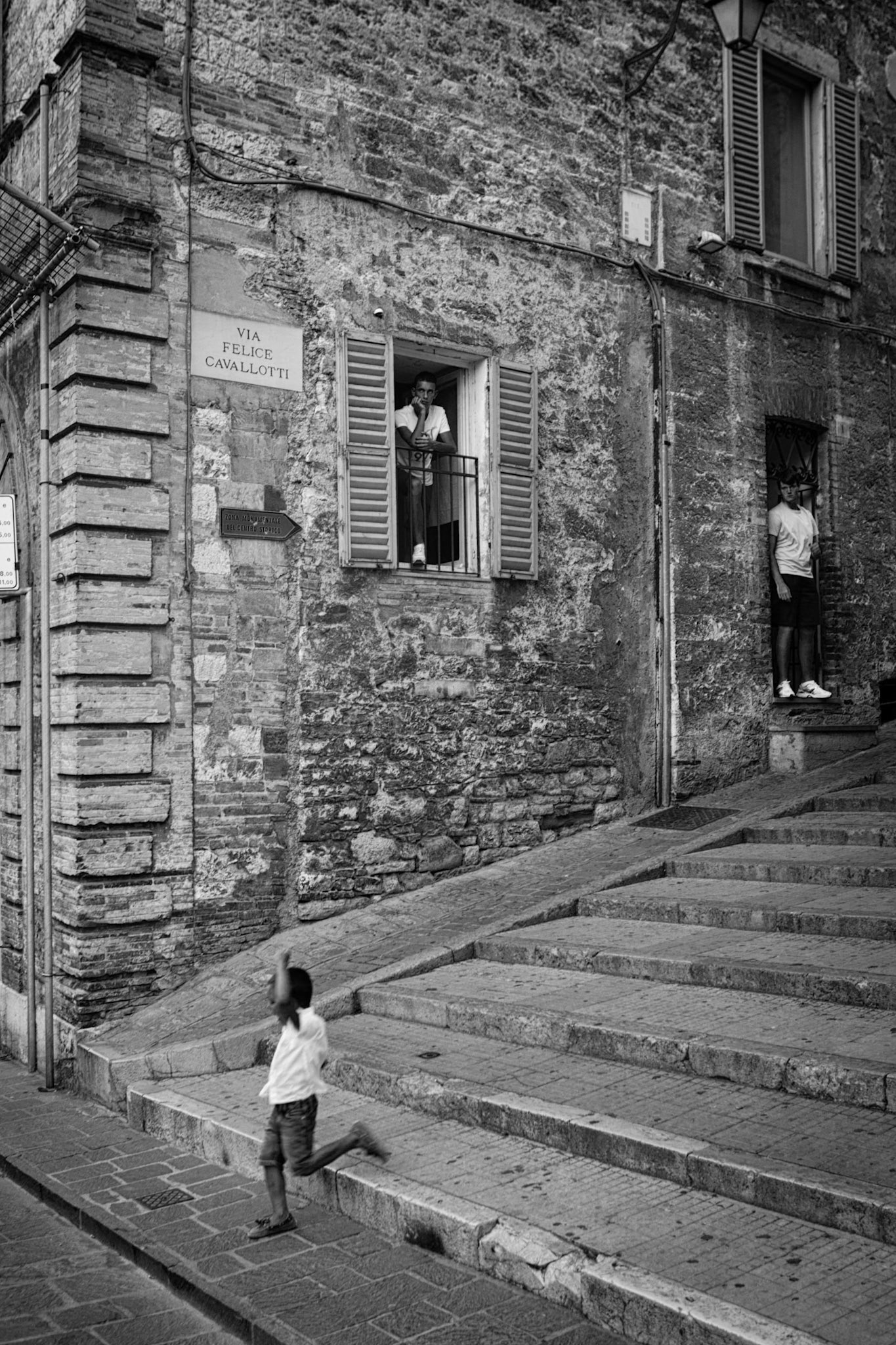 Gubbio, Italy - boy running down the stairs of a medieval street in Gubbyio, two young men watching from a doorway and a window  [url=http://www.istockphoto.com/search/lightbox/11293042#64eec1d][img]http://www.piebinga.nl/banners/italy.jpg[/img][/url]