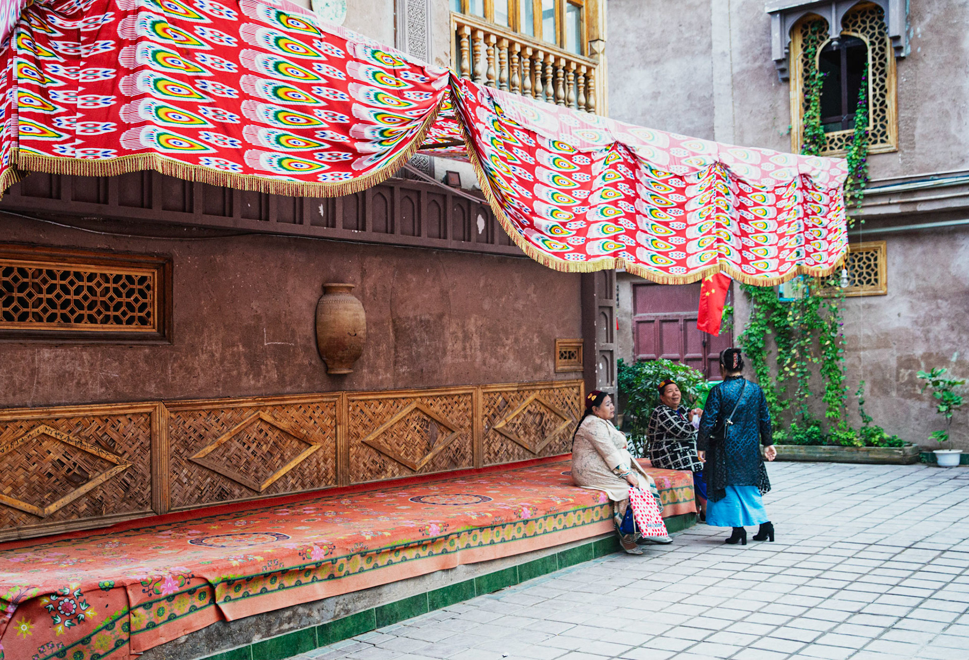 kashgar, Xinjiang, China - September 5, 2018: Three uyghur women, wearing typical dress, chatting on a small square in the old city of Kashgar