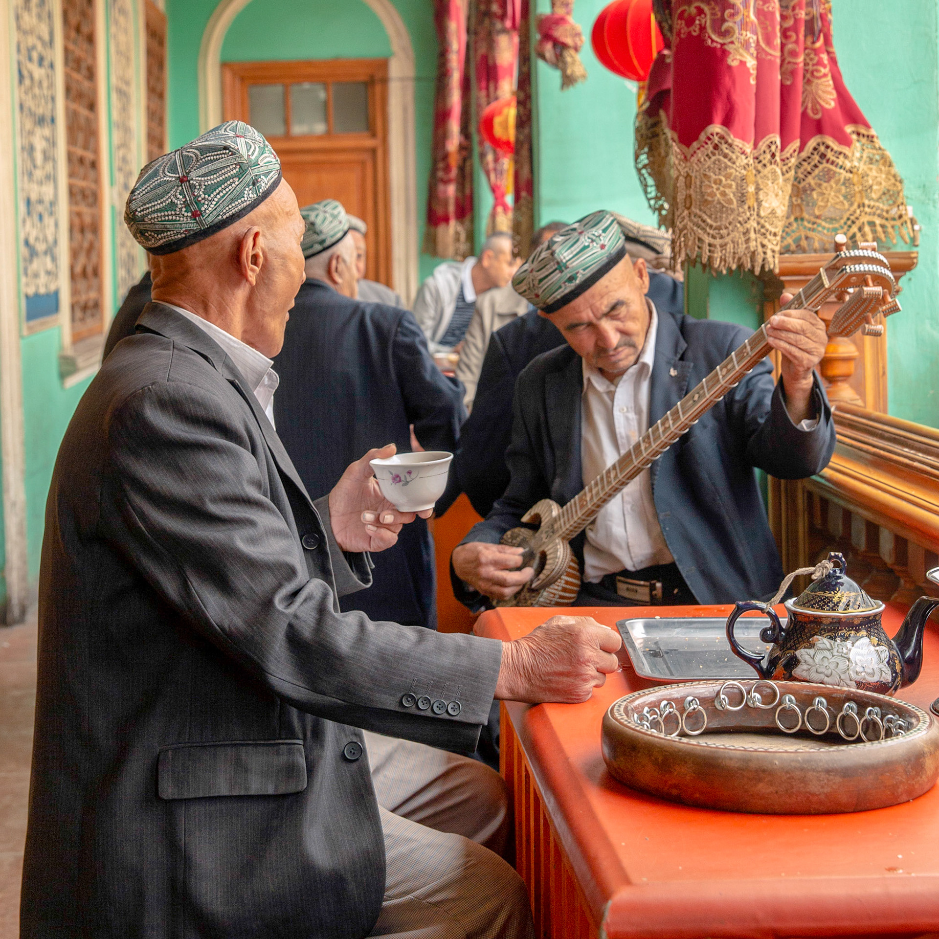 Kashgar, Xinjiang, China - September 5, 2018: Men making music on a 'Rawap" (a short lute with 5 metal strings) and drinking tea in a traditional old tea house in Kashgar