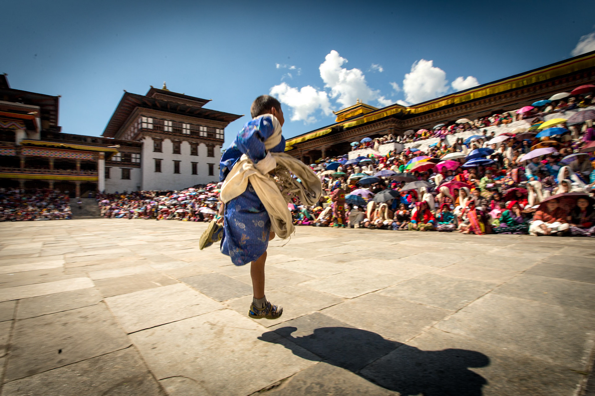 Thimpu, Bhutan - September 27th, 2012 : young boy in traditoinal dress running  on the open space during the Thim;pu  Tschechu religious festival
