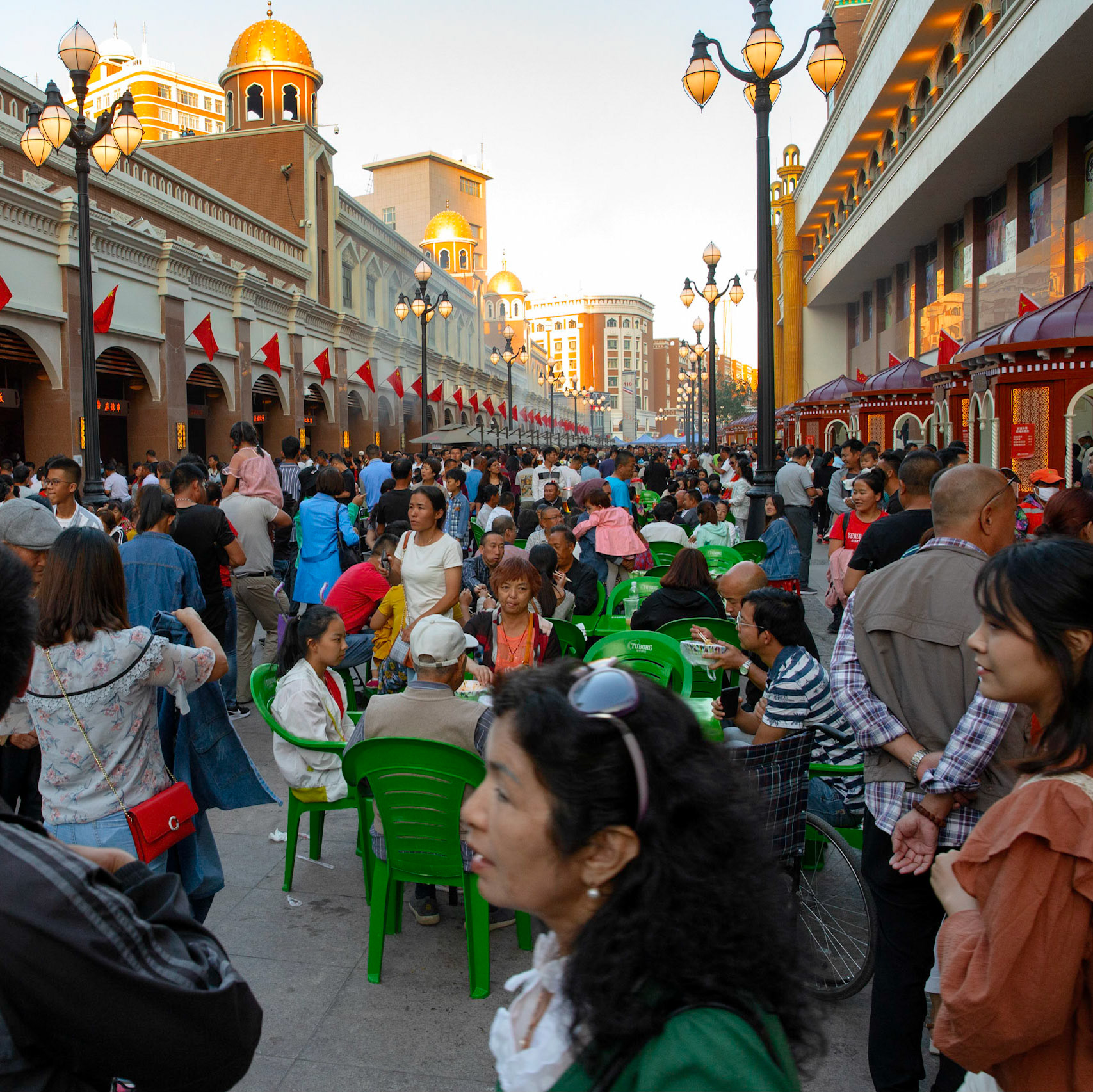 Urumqi, China - september 1, 2018 : People eating food an drinking beer just outside the grand bazaar in Urumqi, the street food stalls are very busy and people gather food from various stalls and eat it together at one of the tables.