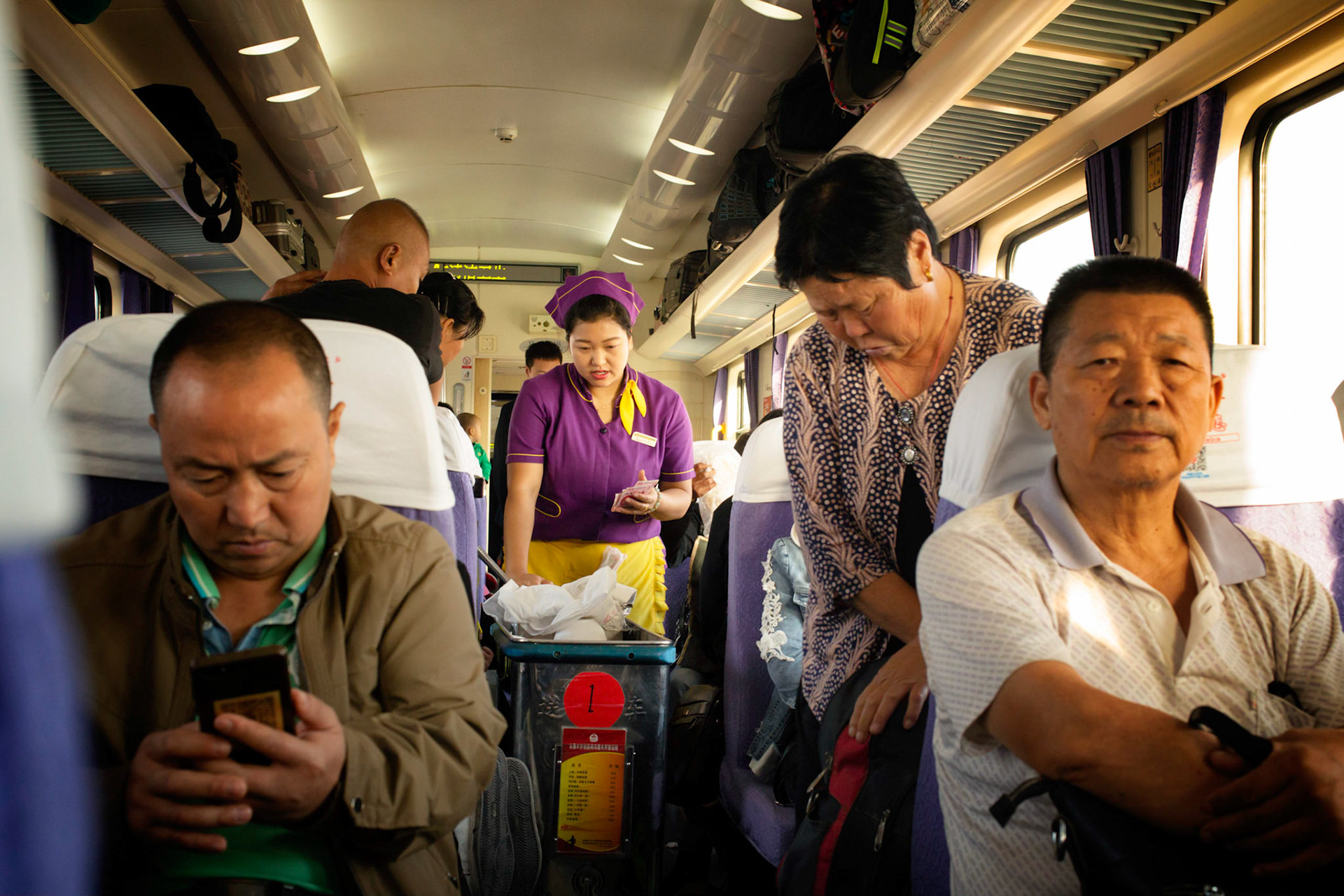 Turpan, Xinjiang, China - september 4, 2018 : Snack and food service in a train in Xinjiang, China, waitress counting money, holding chinese currency, people sitting and checking their phone.