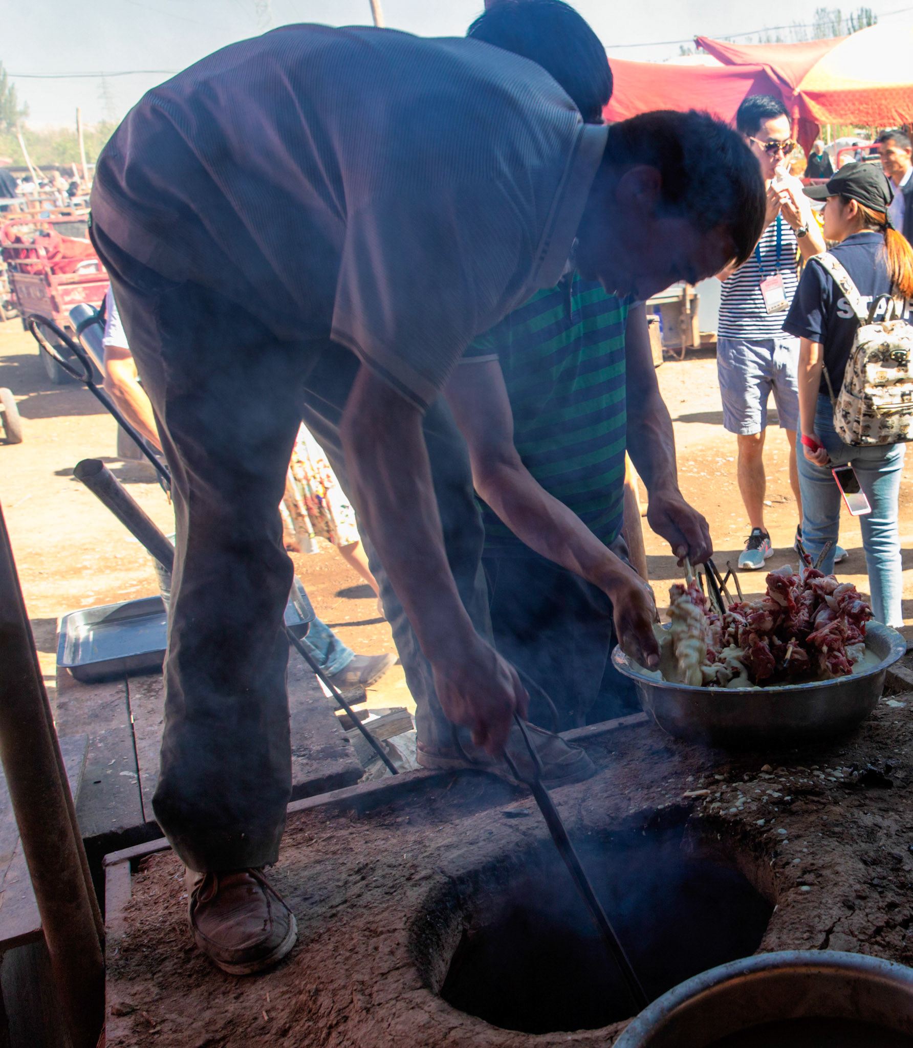 Kashgar,  China - September 9th, 2018 : Man preparing the fire to grill battered lamb meat at the Kasghar cattle market.