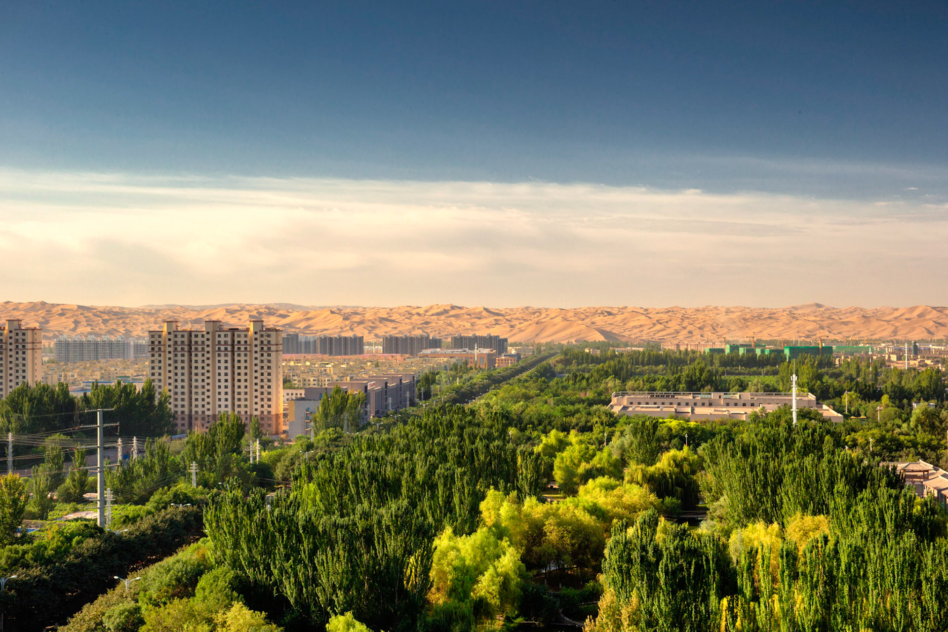 Shanshan, Xinjiang, China - september 3, 2018: Kumtag desert seen from Shanshan, one can see the green oasis abruptly ending in sand mountains