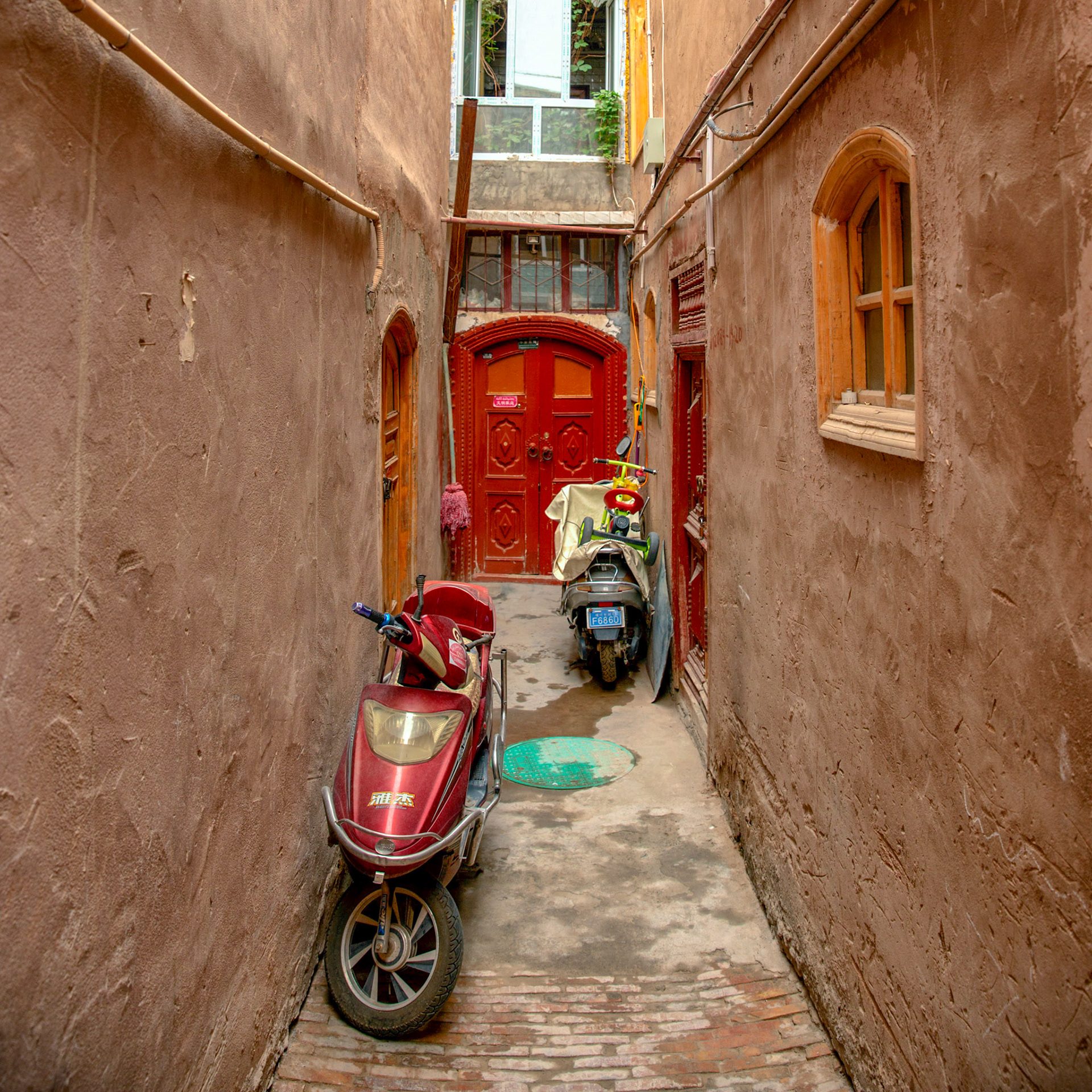 Kashgar, Xinjiang, China - September 5, 2018: Scooters parked in a small alleyway in Kashgar, Xinjiang, China.