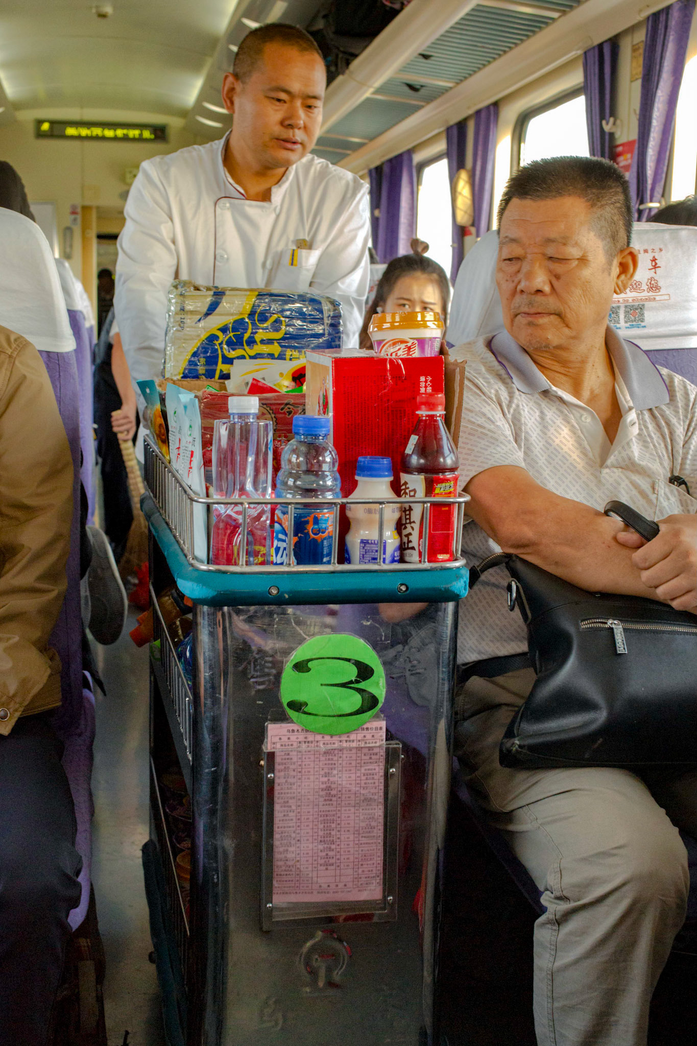 Turpan, Xinjiang, China - september 4, 2018 : Snack and food service in a train in Xinjiang, China, uniformed waiter pushing a trolley through the middel path.