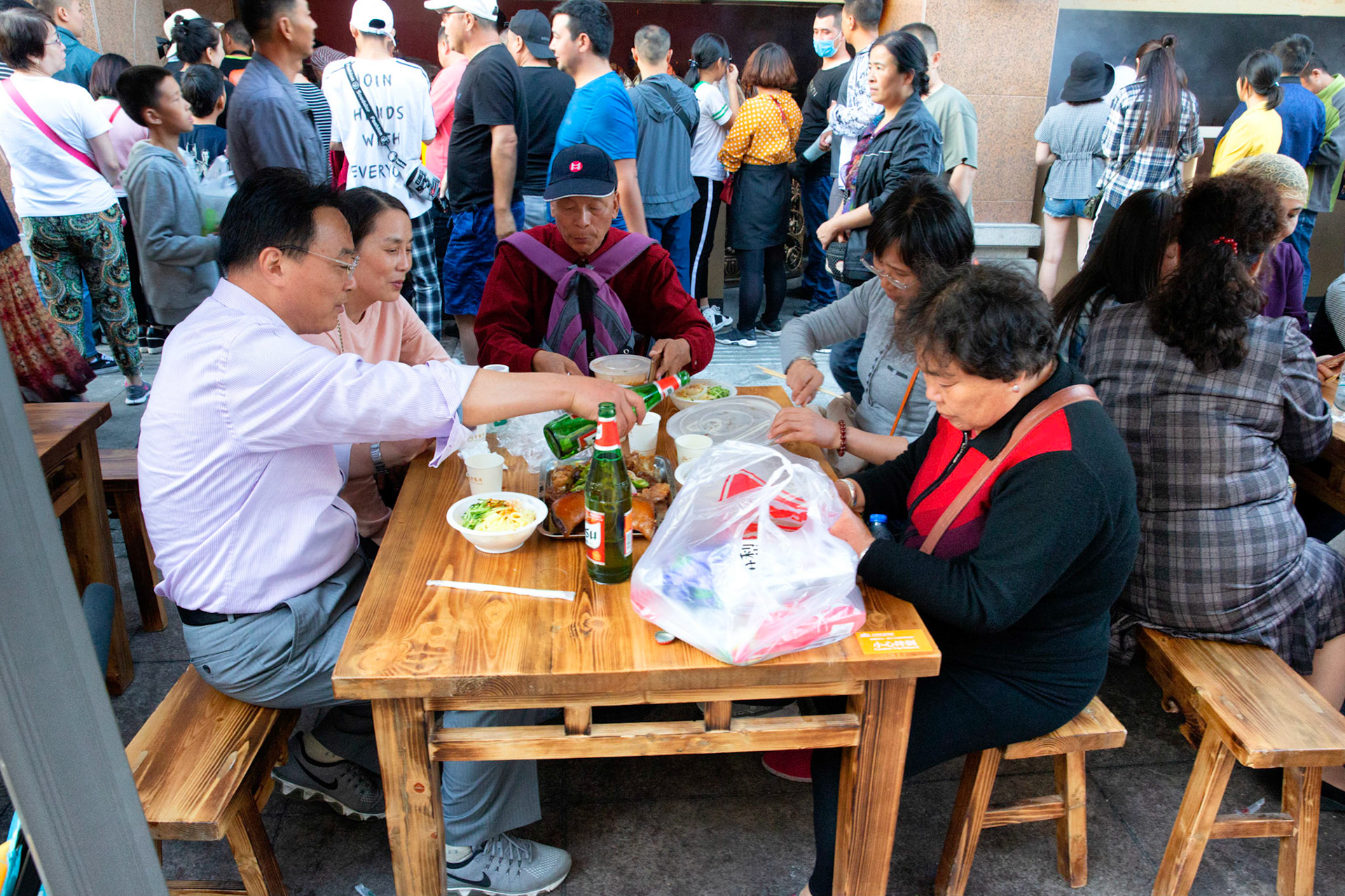 Urumqi, China - september 1, 2018 : People eating food an drinking beer just outside the grand bazaar in Urumqi, the street food stalls are very busy and people gather food from various stalls and eat it together at one of the tables.
