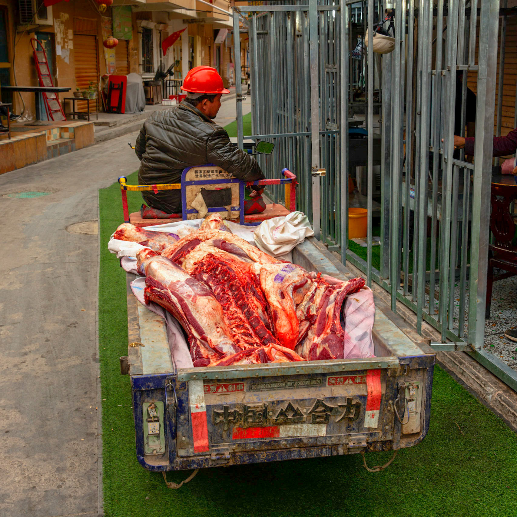 Kashgar, Xinjiang, China - September 5, 2018: Meat being transported in a small 3-wheeled vehicle through the streets of Kashgar.