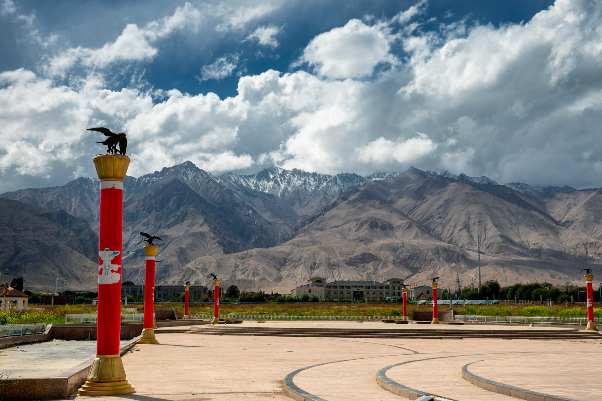 Tashgurkan, China - September 7th, 2018 : big square for festivals or social gatherings in Tashgurgan, hotel on teh background. Note the typical Tajik eagles on the pillars.