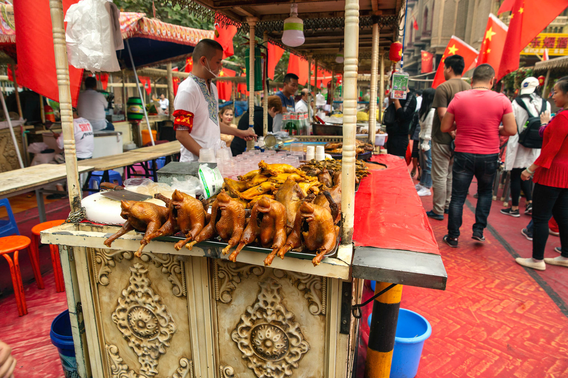 Kashgar, Xinjiang, China - September 5, 2018: Ma grilled chickens ready at a food stall in the Kashgar food market, note the abundance of Chinese flags.