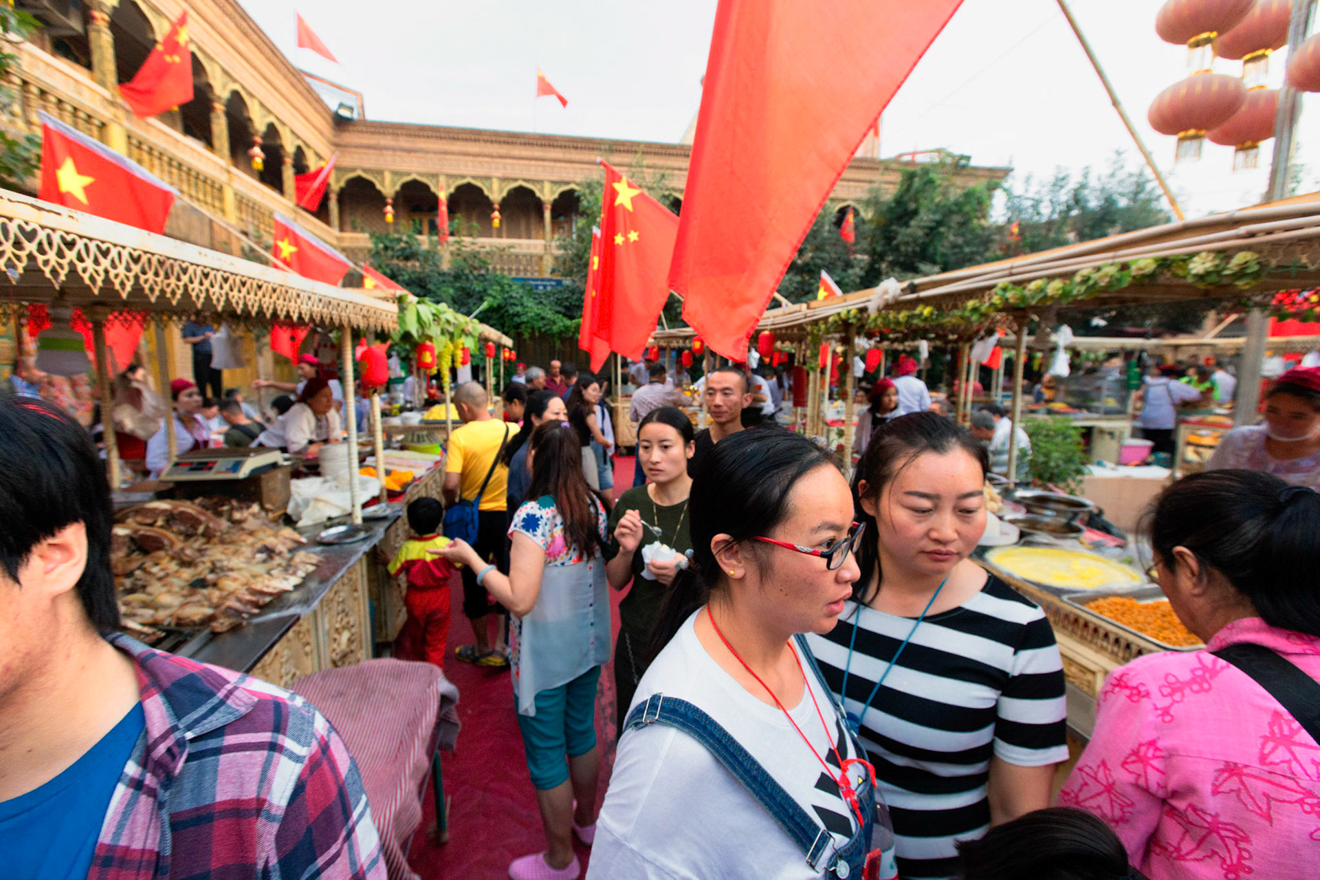 Kashgar,  China - September 11th, 2018 : People enjoying food at the Kashgar food market, many food stalls and many chinese flags