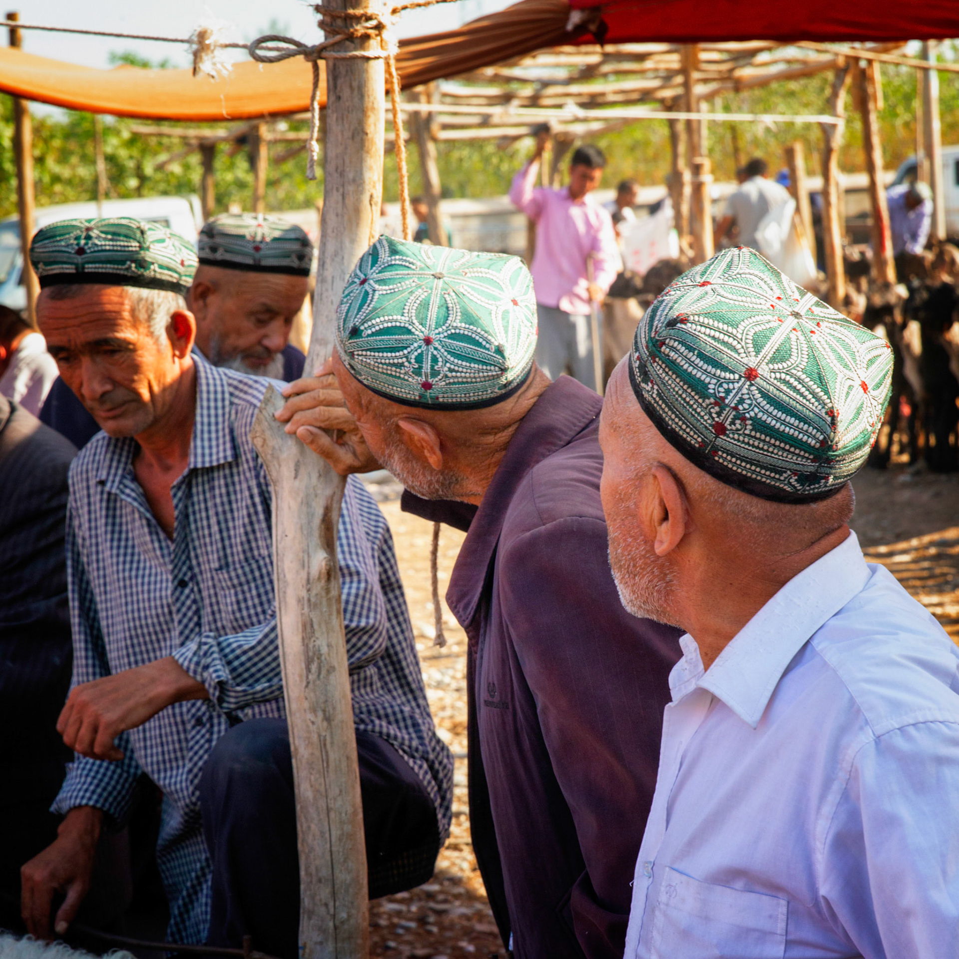 Kashgar,  China - September 9th, 2018 : Men wearing traditional uyhur hats, chatting at the sunday cattle market.