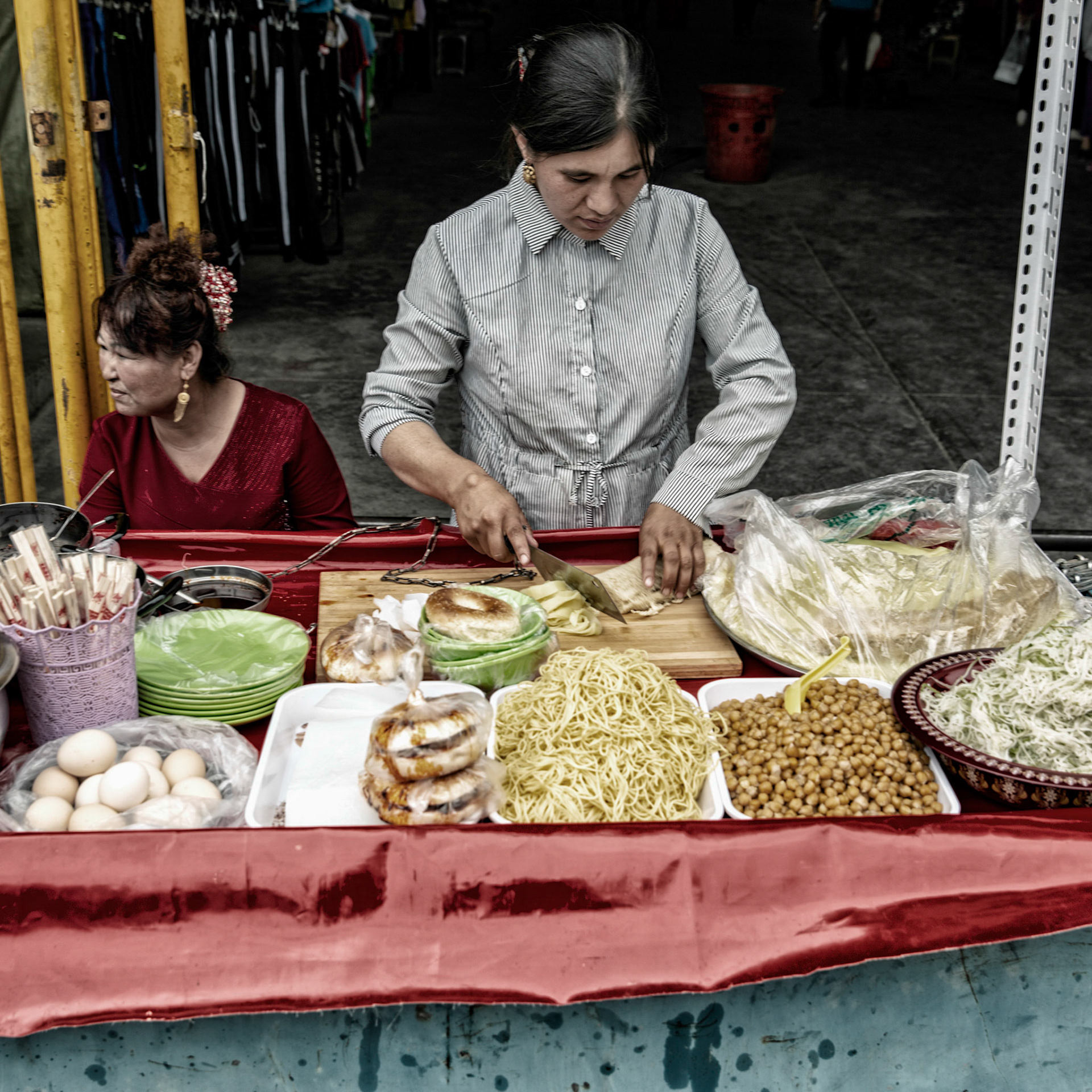 Kashgar, Xinjiang, China - September 5, 2018: Woman preparing cold noodles at the Kashgar night bazaar