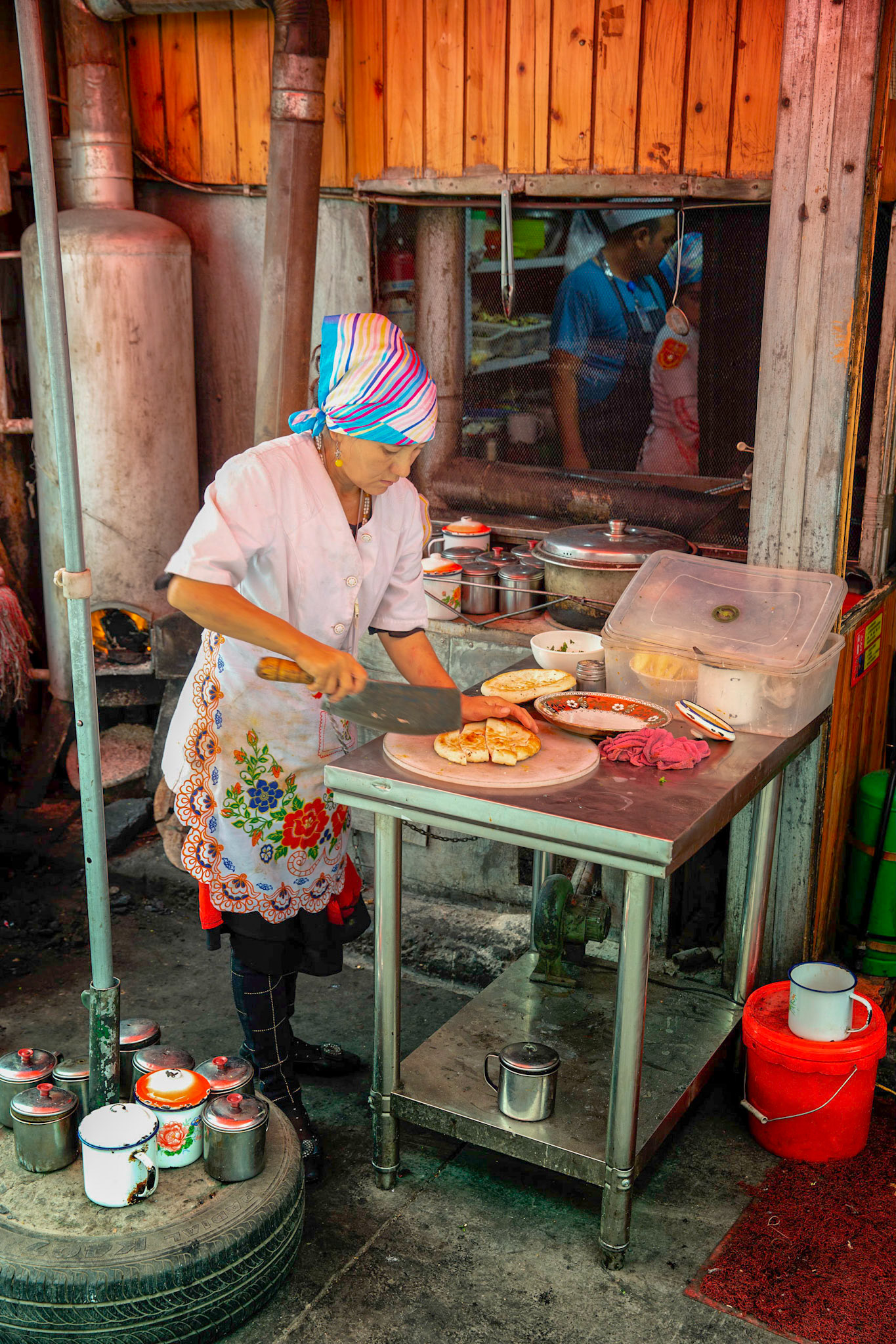 Kashgar, Xinjiang, China - September 5, 2018: Woman preparing food at a food stall in the Kashgar Grand Bazaar