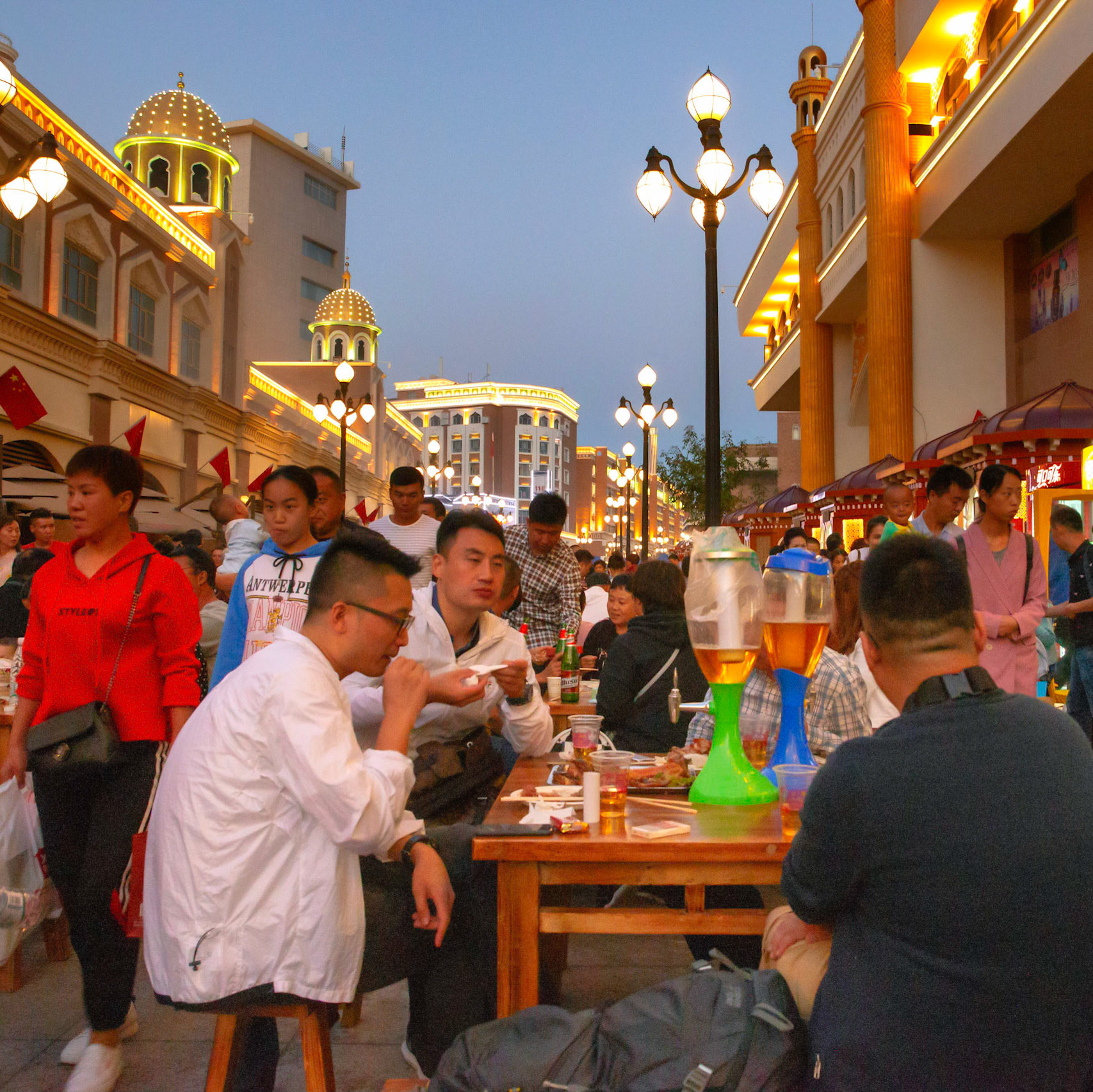 Urumqi, China - september 1, 2018 : People eating food an drinking beer just outside the grand bazaar in Urumqi, the street food stalls are very busy and people gather food from various stalls and eat it together at one of the tables.