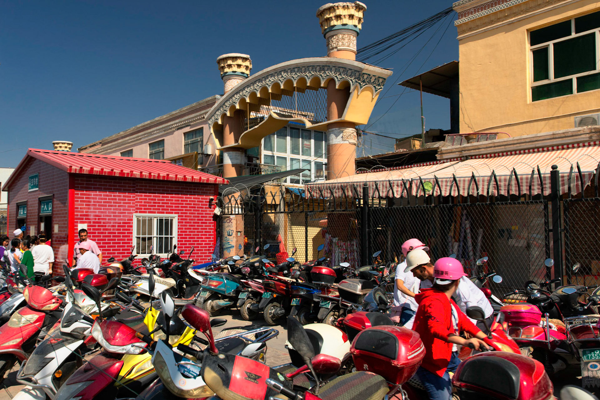 Kashgar,  China - September 10th, 2018 : Motorcycles parked in front of the Grand Bazaar in Kashgar, the red building in the background is the entry checkpoint where police performs identity checks.