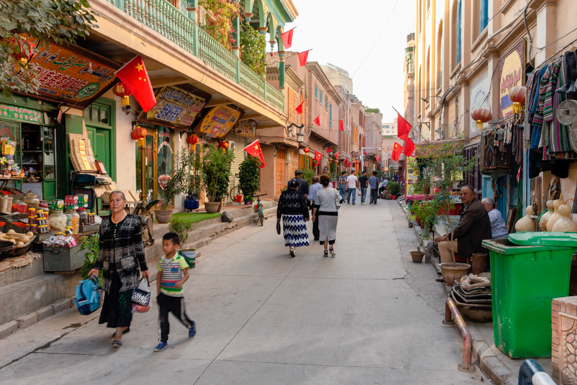 Kashgar,  China - September 8th, 2018 : People walking the streets in the Kashgar old town, many chinese flags hanging from the houses and shops.