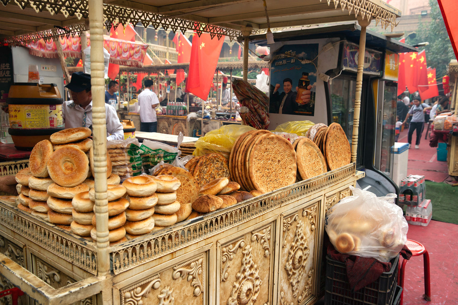 kashgar, Xinjiang, China - September 5, 2018: Food stall Kasghar food market, Nan bread stall. Note the chinese flags in the background.