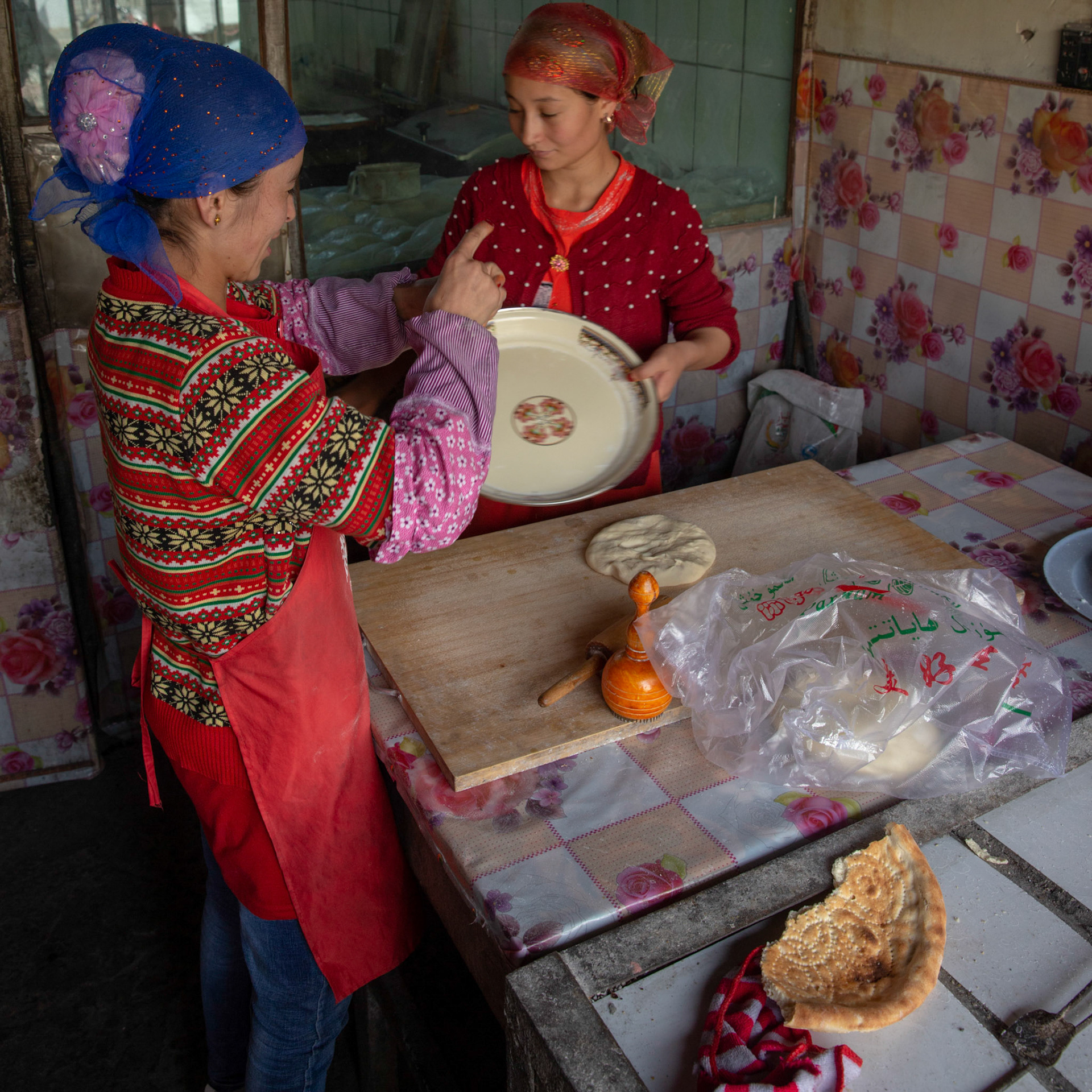Tashgurkan, China - September 7th, 2018 : Two women preparing food  in a kitchen in Tashgurkan.