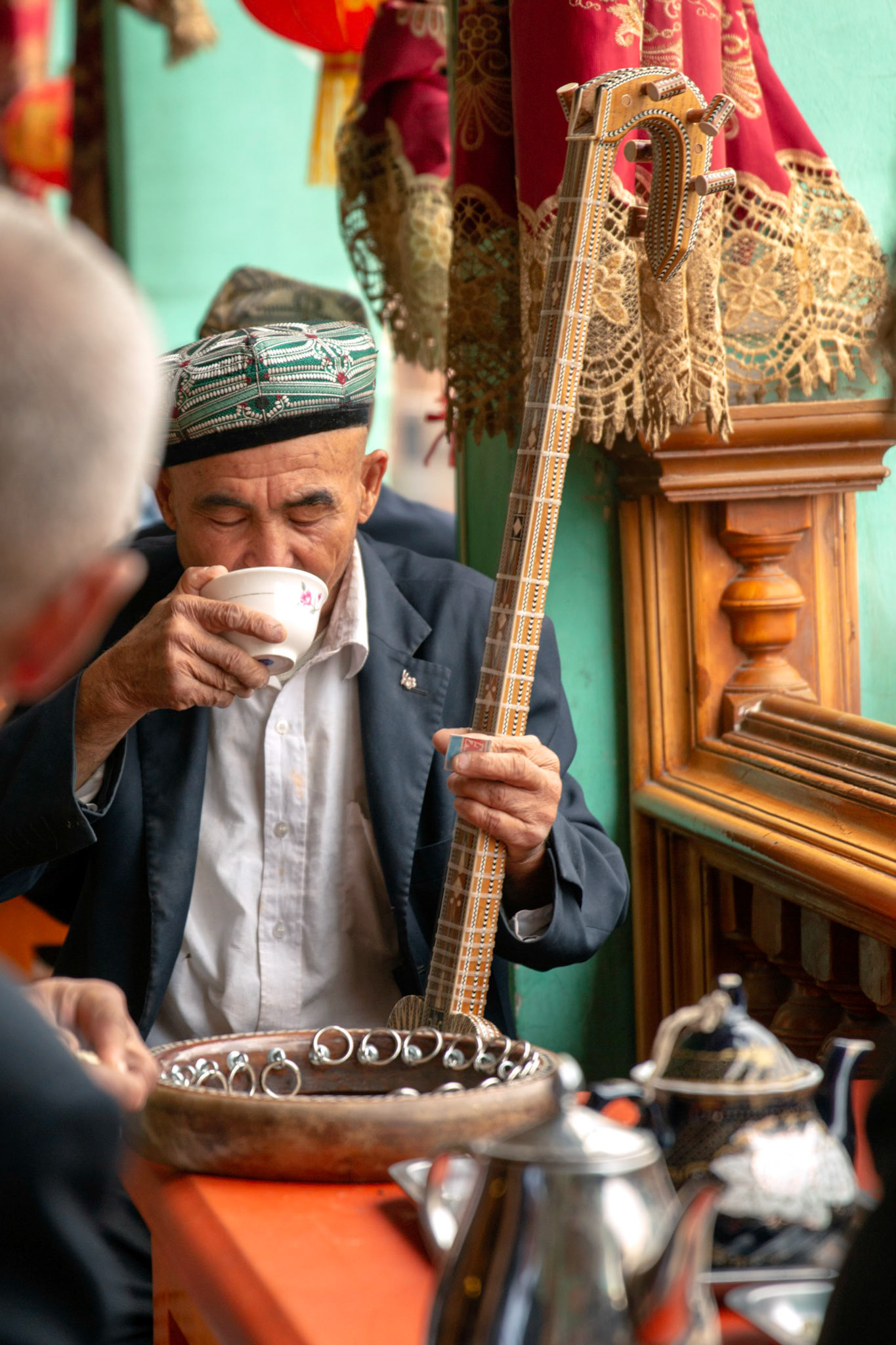 Kashgar, Xinjiang, China - September 5, 2018: Men making music on a 'Rawap" (a short lute with 5 metal strings) and drinking tea in a traditional old tea house in Kashgar