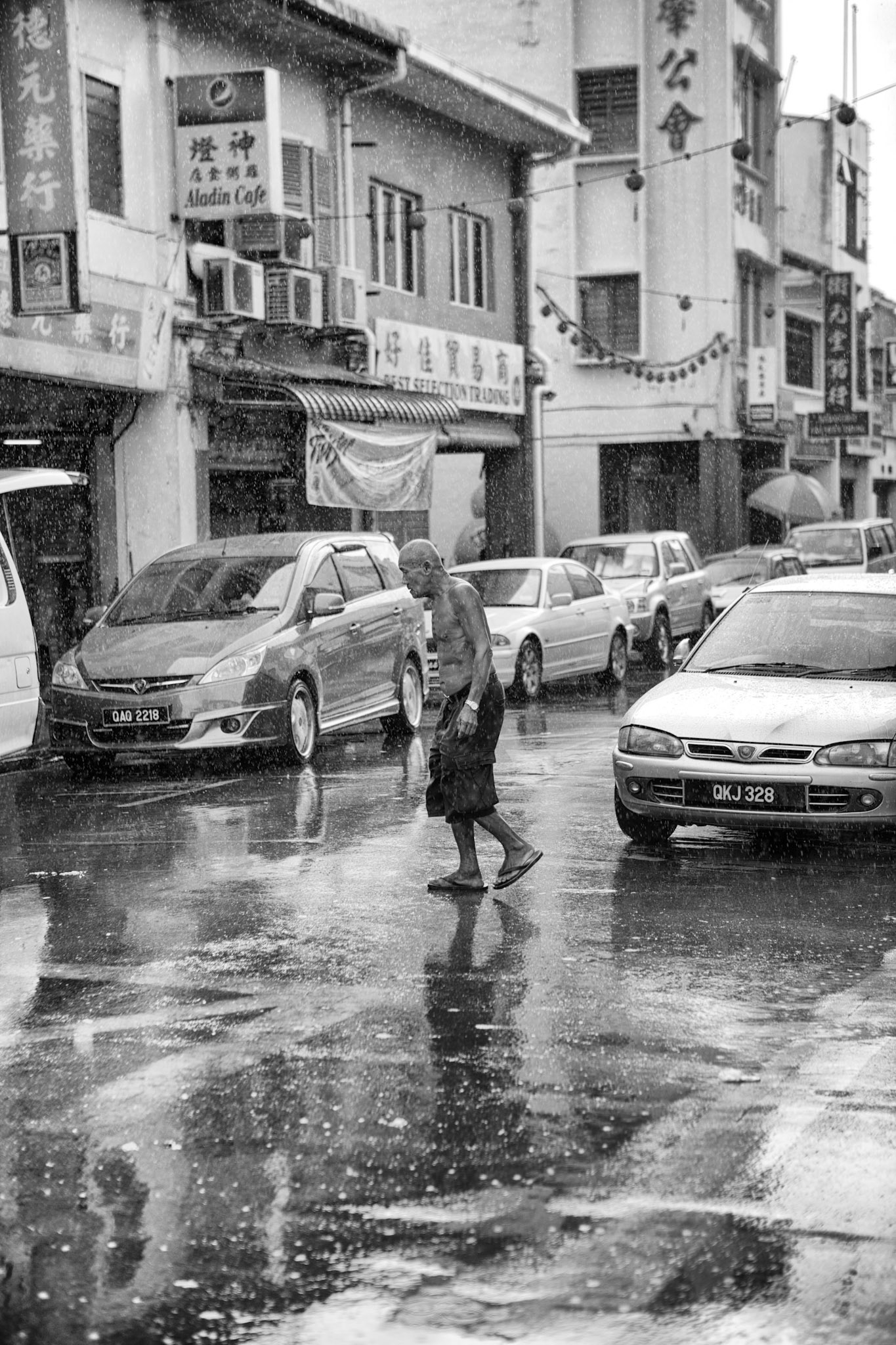 Malaysia, Kuching - March 8th, 2012 : man crossing the road in Kuching during a tropical rainshower [url=http://www.istockphoto.com/search/lightbox/12391109#11fcd736][img]http://www.piebinga.nl/banners/borneo.jpg[/img][/url]
