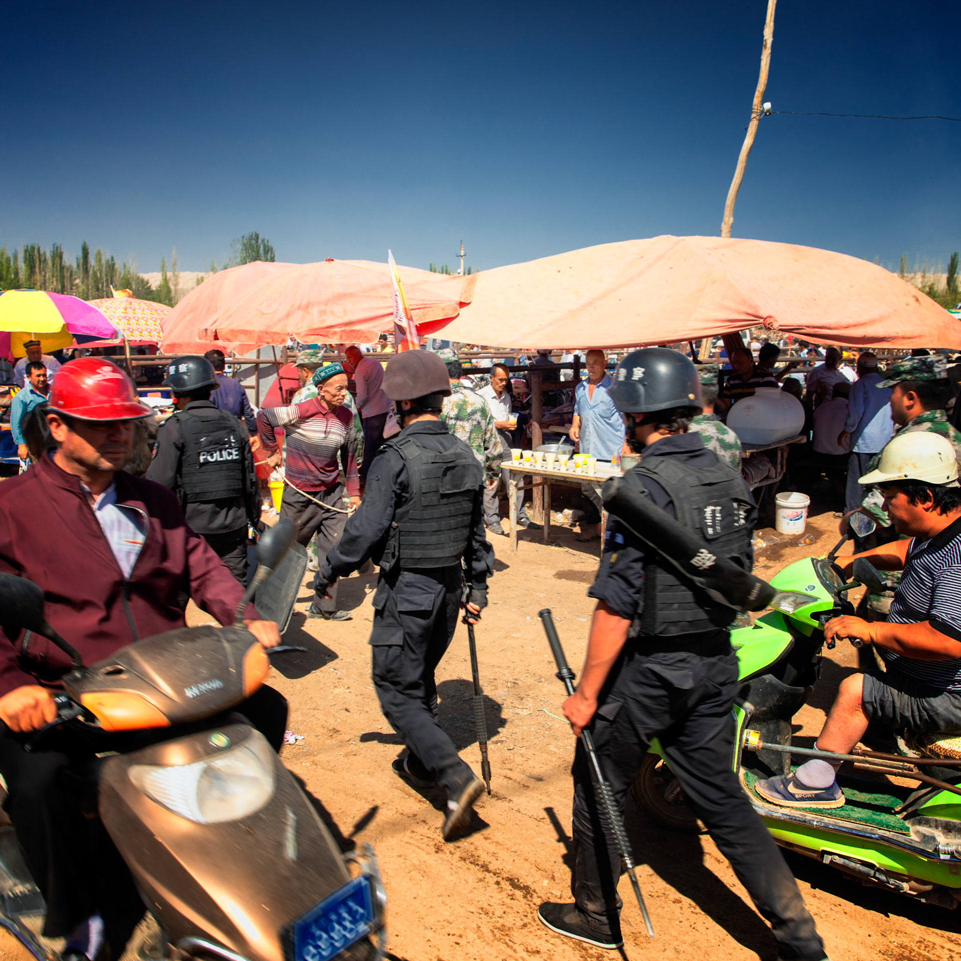 Kashgar,  China - September 9th, 2018 : Small group of security police patrolling the Kashgar sunday bazaar (sunday cattle market), carrying iron batons.