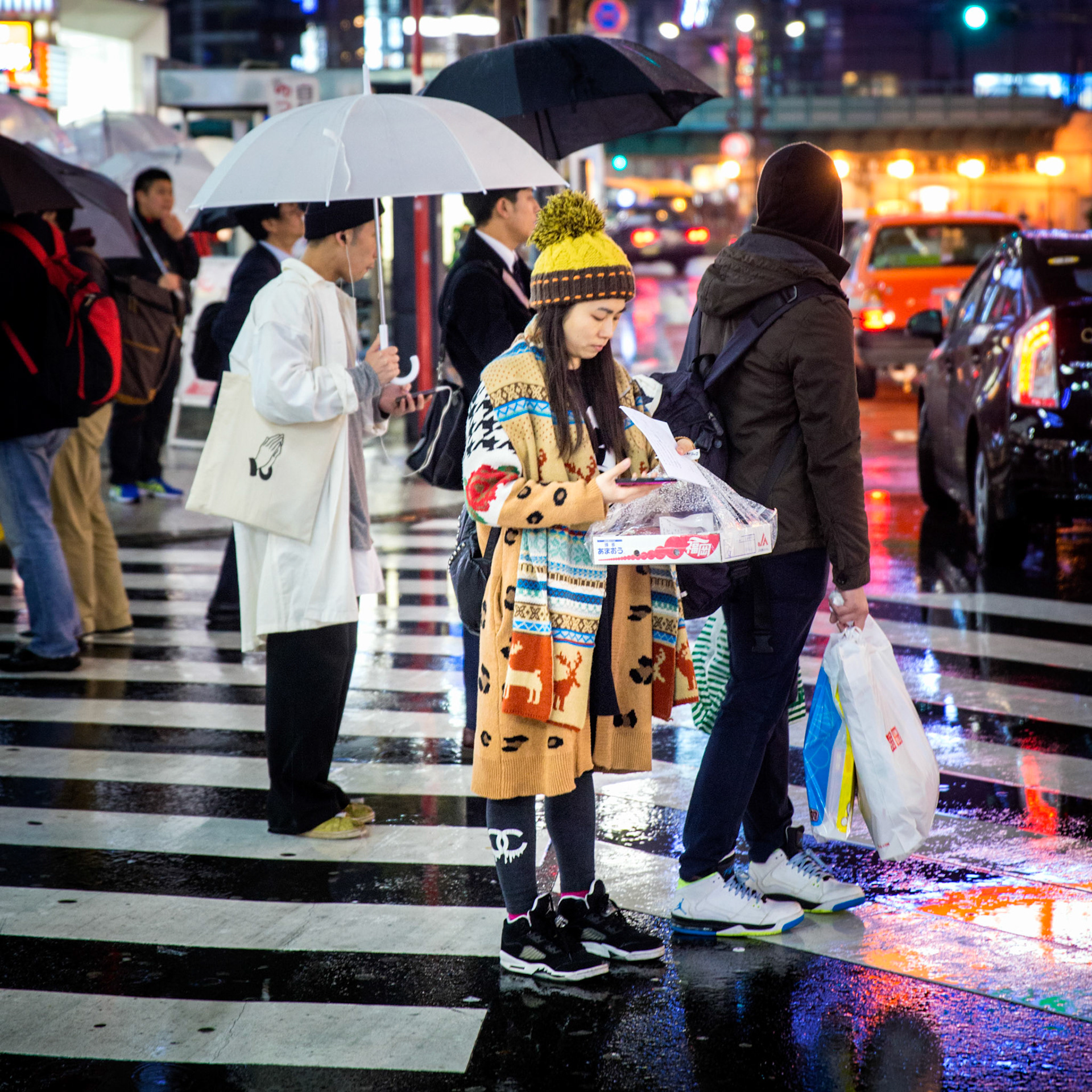 Tokyo, Japan - April 10, 2015 : girl wearing colourful clothes, standing at a  tokyo zebra crossing, crowd and neon light in the background