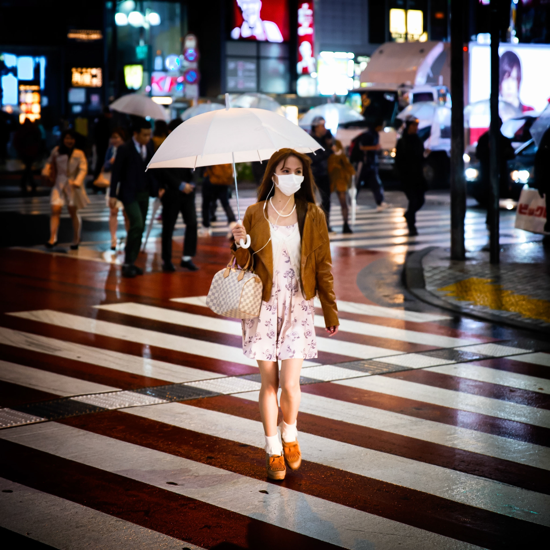 Tokyo, Japan - April 7, 2015 : Girl holding umbrella, walking on a zebra crossing in the Shinjuku district, crowd in the background