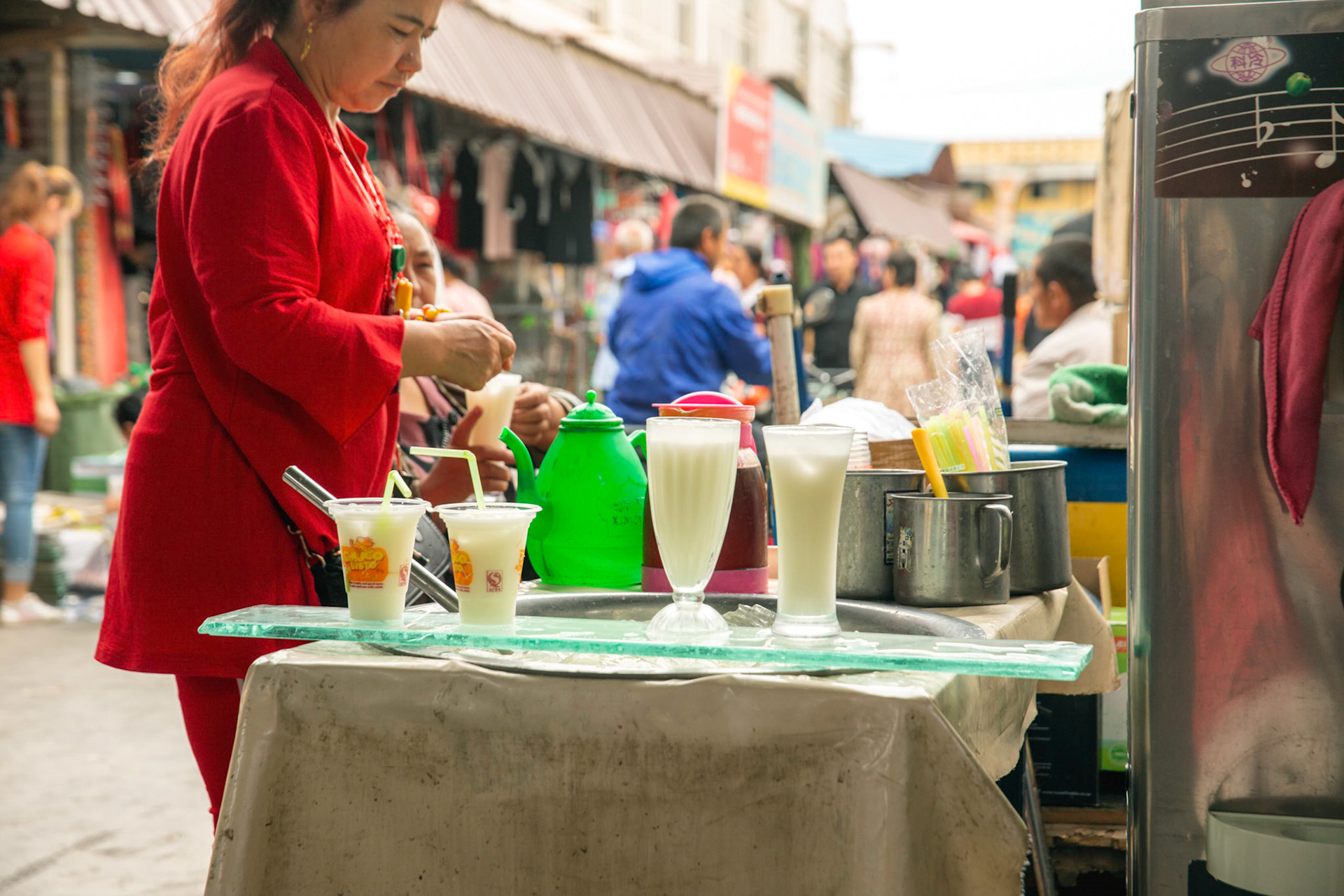 Kashgar, Xinjiang, China - September 5, 2018: Woman buying a yoghurt drink in the Kashgar Grand Bazaar