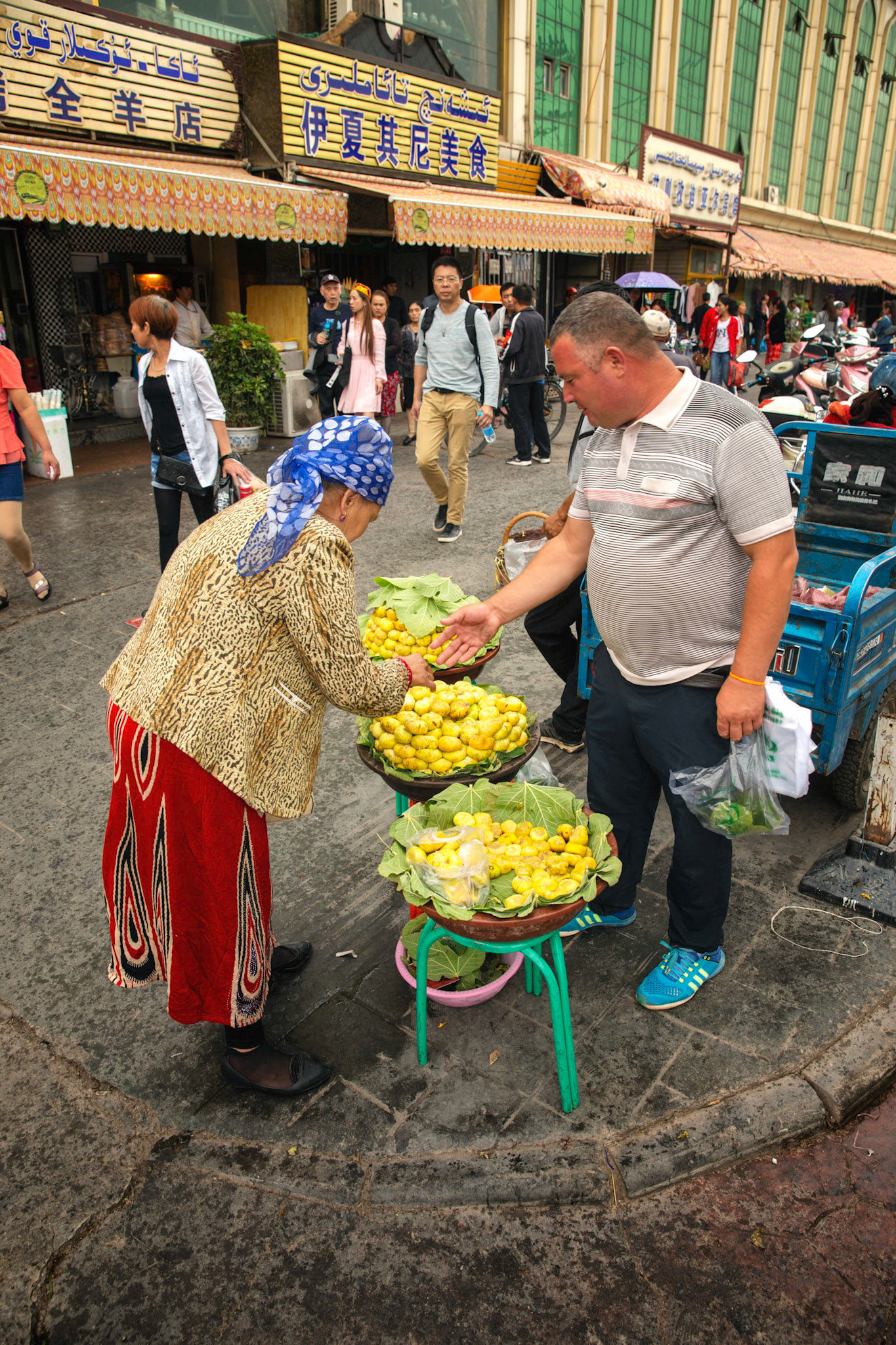 Kashgar, Xinjiang, China - September 5, 2018: Woman wearing a head scarf buying figs at the Kashgar Market.